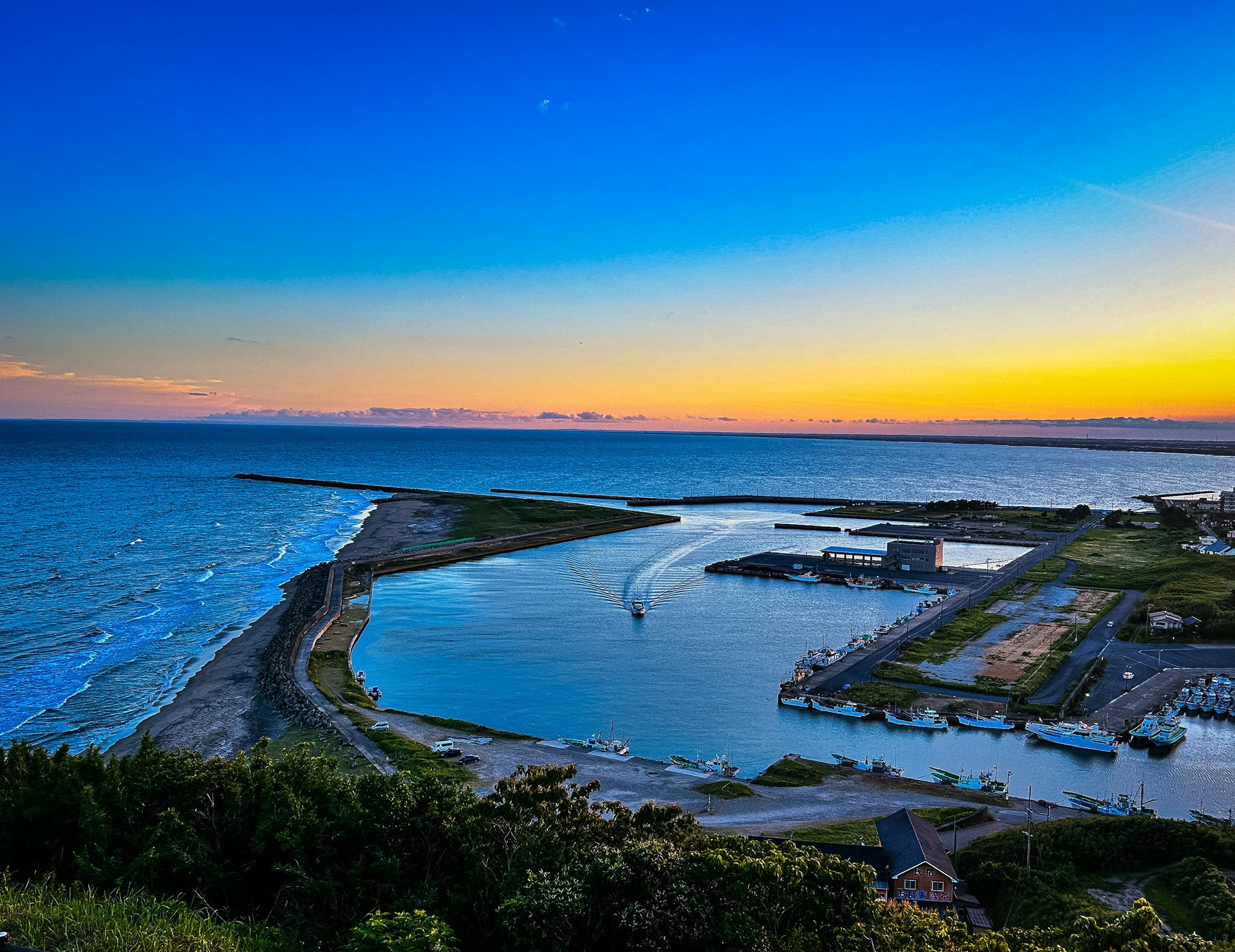 夕暮れの海沿いの港と防波堤のある湾の風景