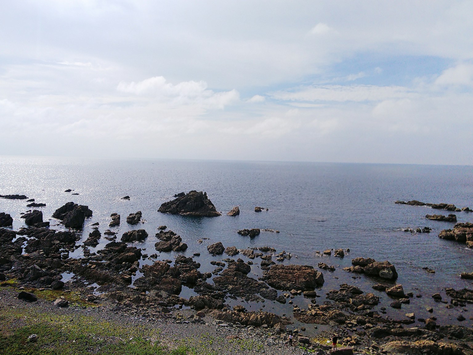 穏やかな海と岩の景色 青い空と薄い雲の背景