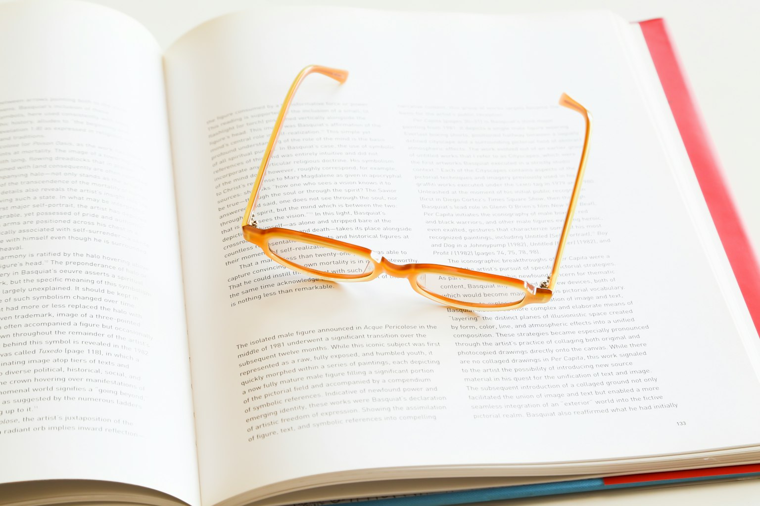 Kacamata oranye yang terletak di atas buku terbuka