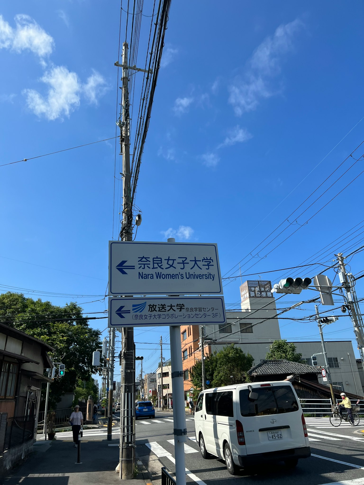 Cartel universitario bajo un cielo azul claro con paisaje urbano