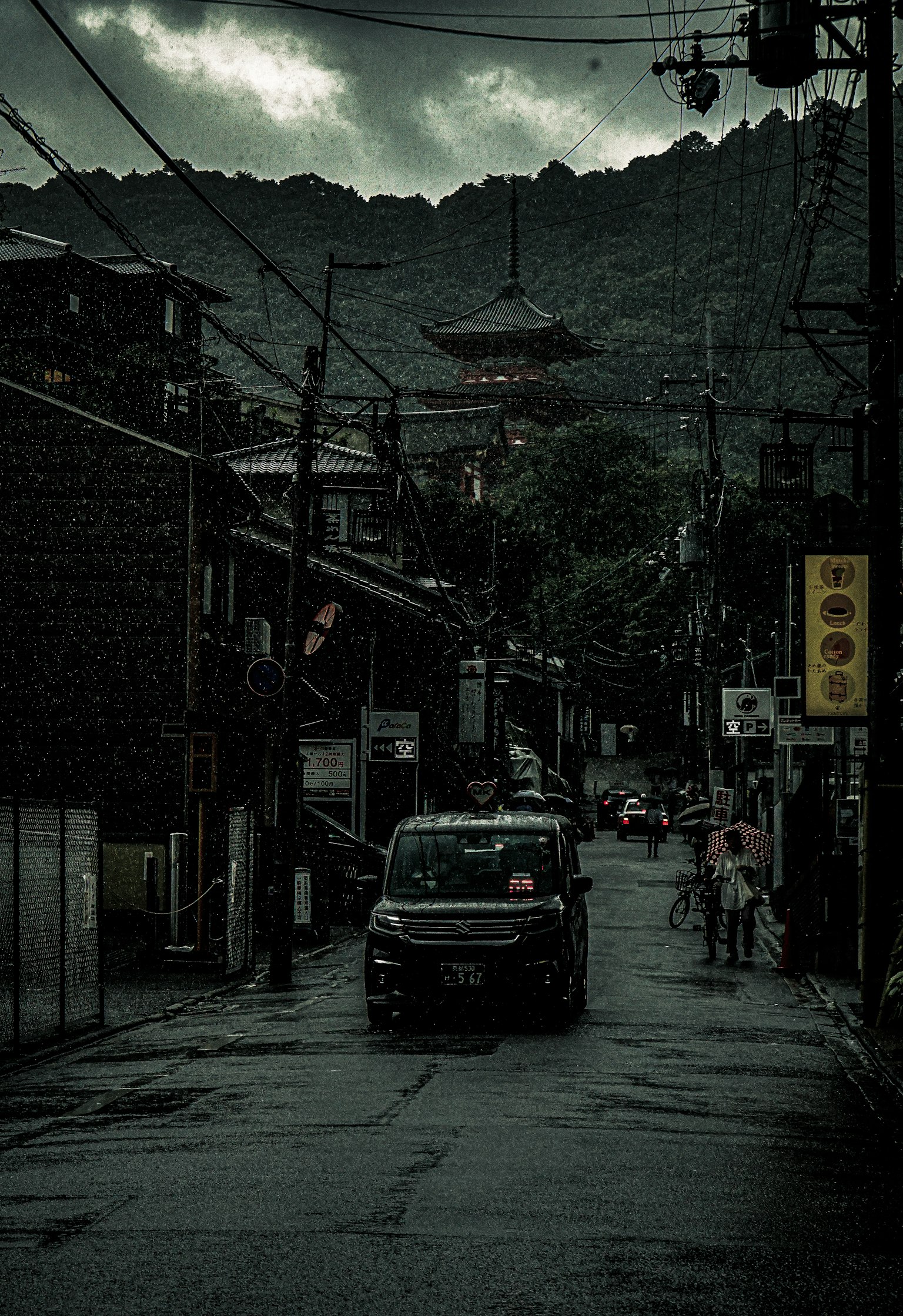 在阴云下，山脉背景中，汽车驶过古老街道的美景