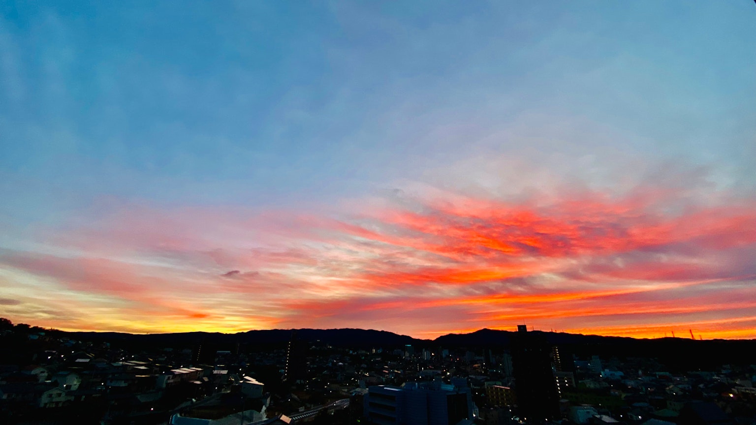 A stunning sunset sky with vibrant orange and pink clouds stretching across the horizon
