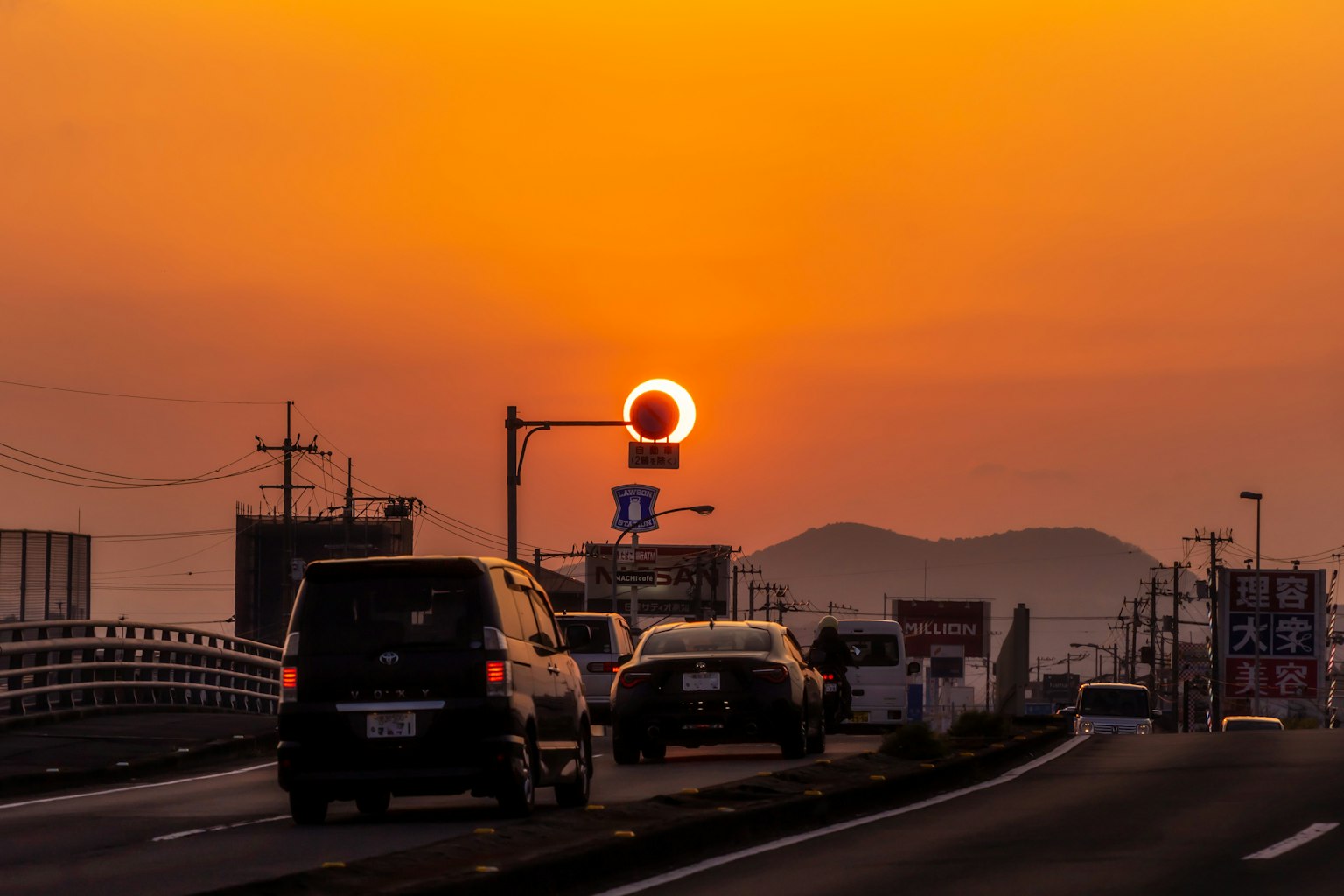 Tramonto su un'autostrada con auto e segnali stradali