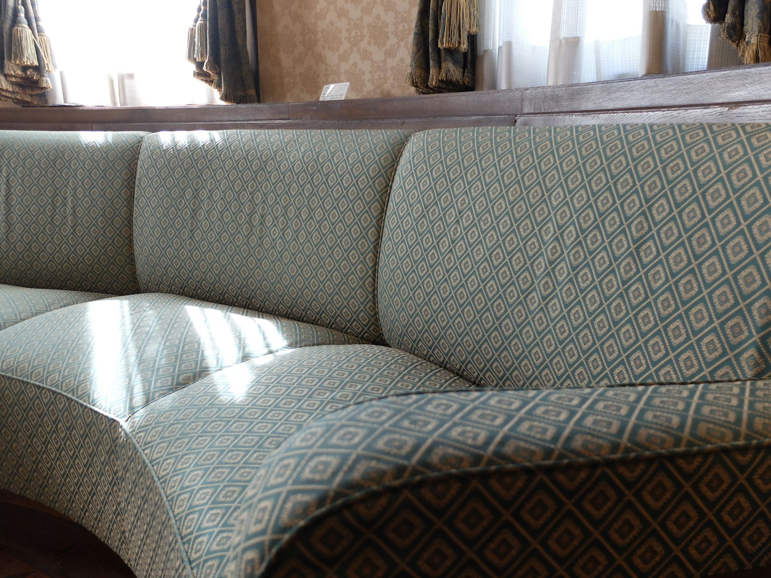 Phần của ghế sofa cong với họa tiết vải tinh xảo và ánh sáng mặt trời chiếu qua cửa sổ
