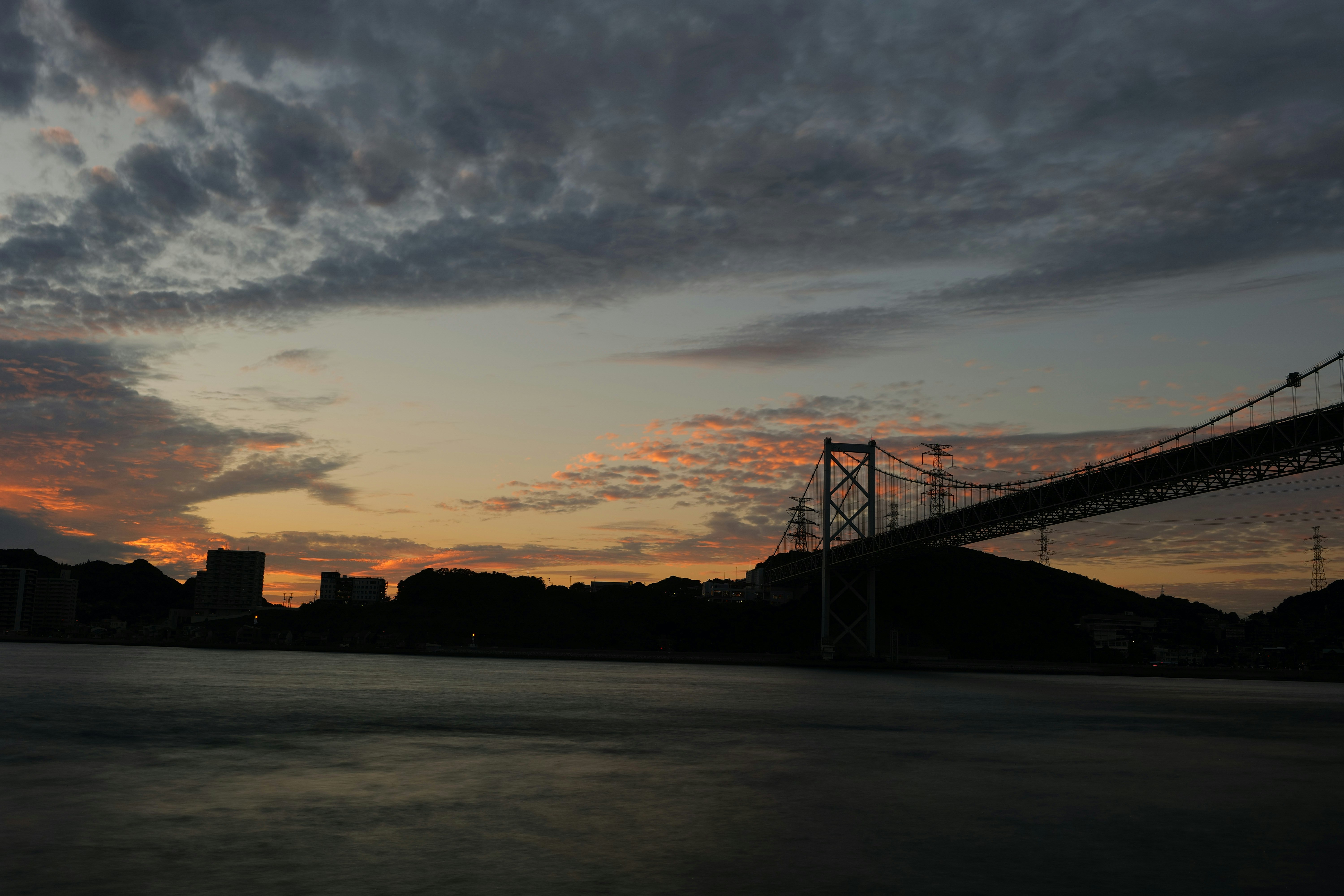 関門橋を望む夕焼けの空と海沿いの道路