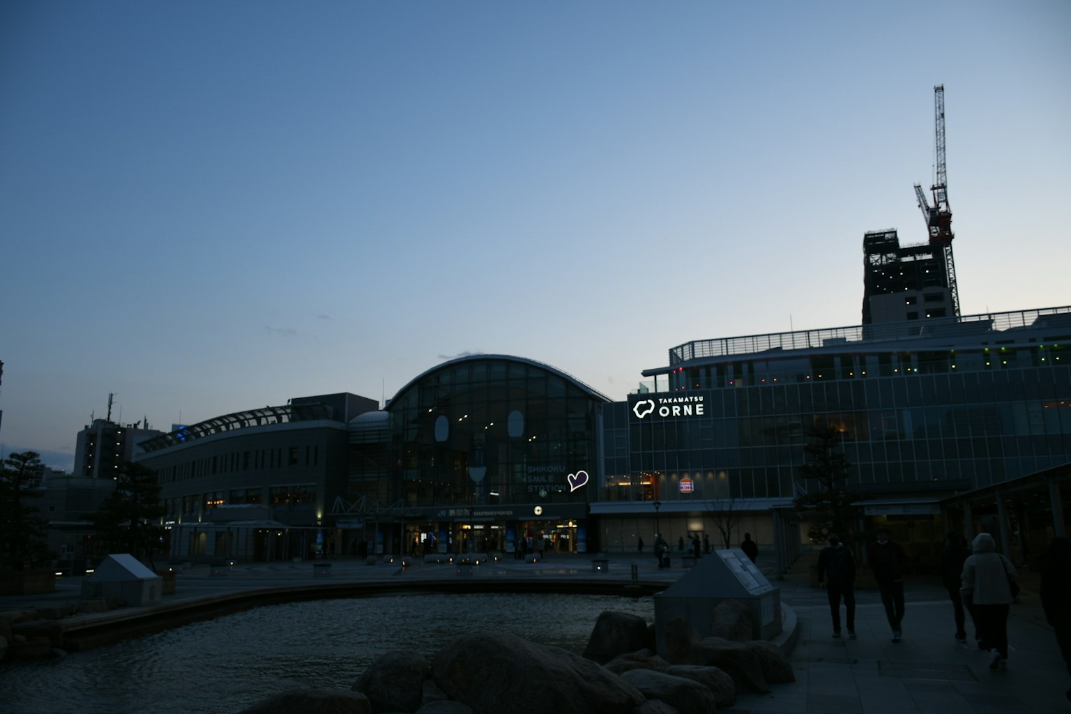 Night view of a train station with surrounding people