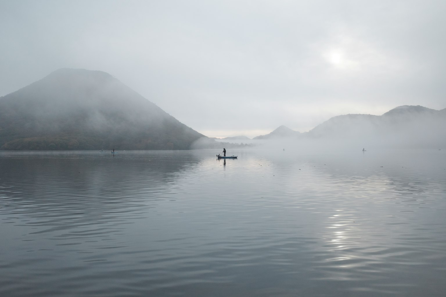 Un lago sereno con una piccola barca che deriva nella nebbia