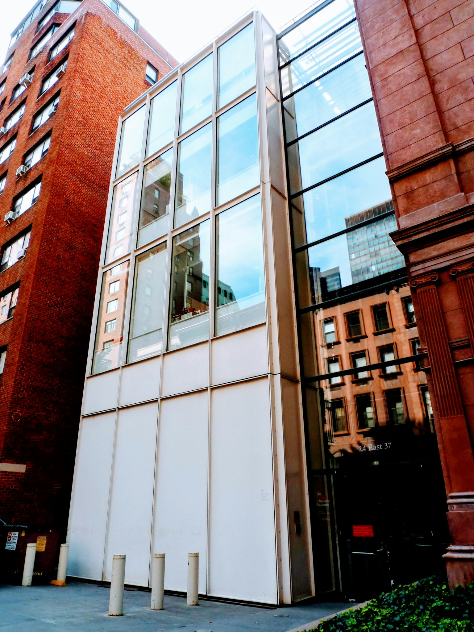 Modern glass building with surrounding red brick structures