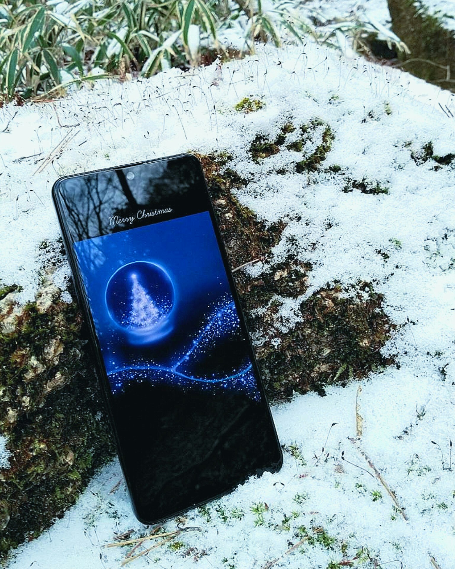 Smartphone auf schneebedecktem Boden mit blauem Display
