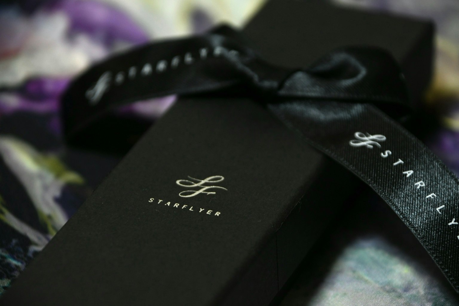 Primo piano di una scatola regalo nera con il logo Starley e un nastro