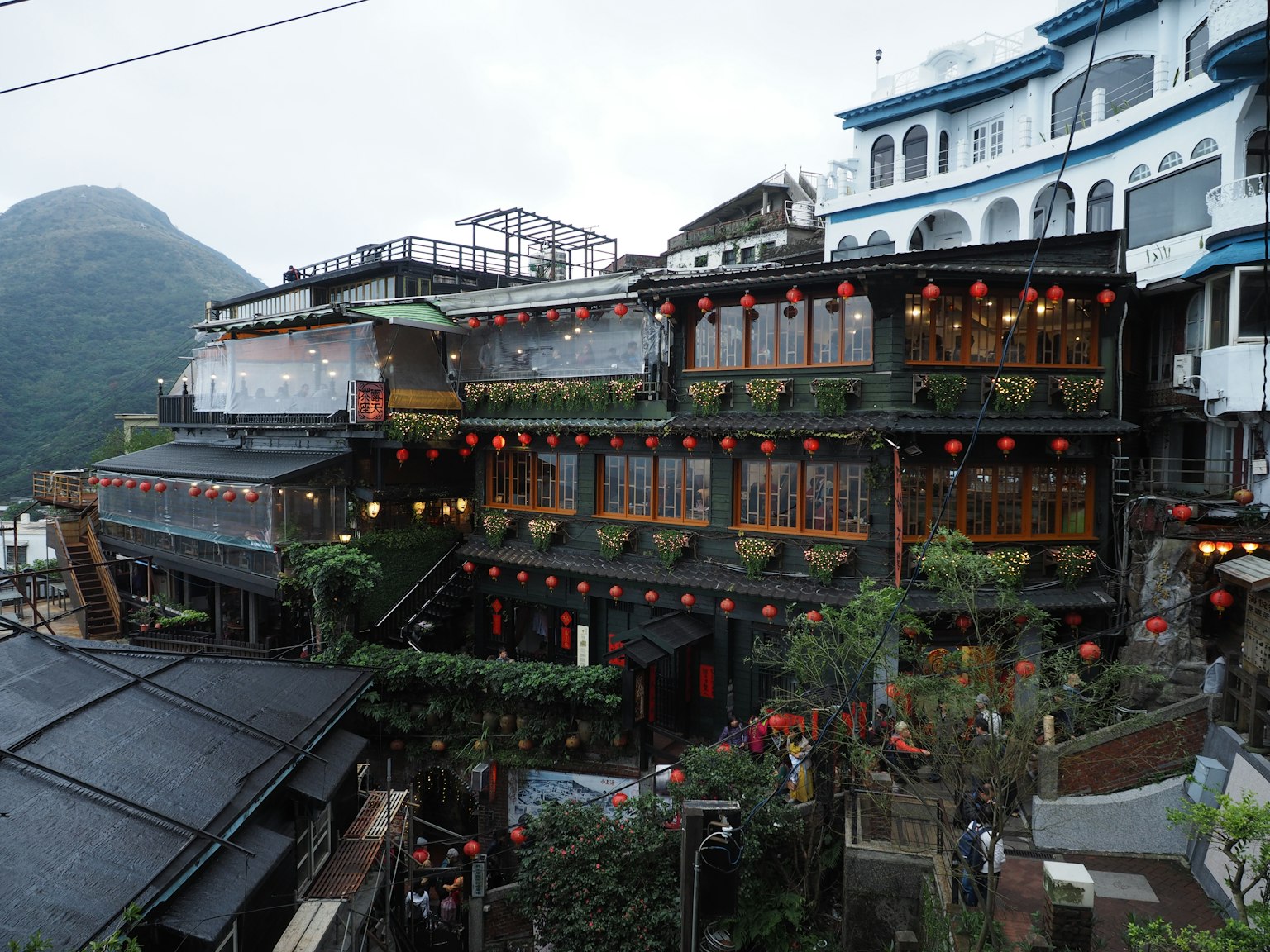 Scenic view of traditional buildings with red lanterns surrounded by mountains