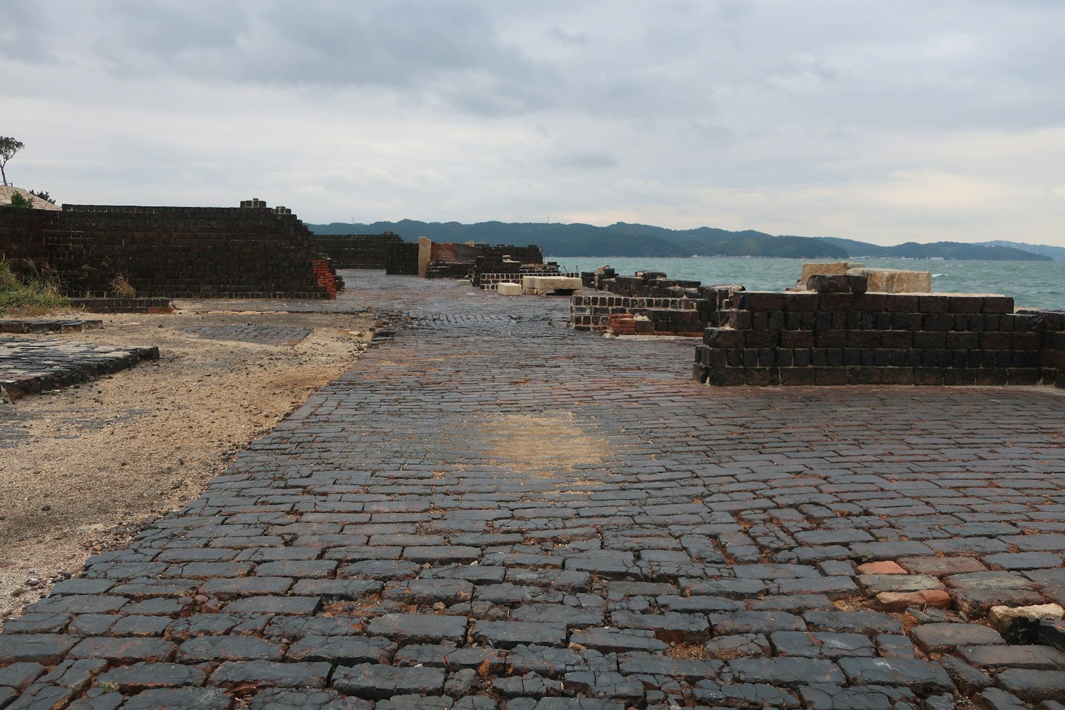 Scenic view of an old cobblestone path by the sea with irregular bricks