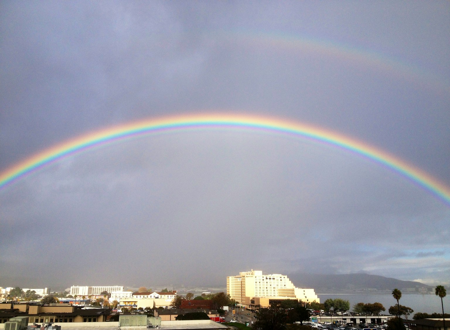 Un double arc-en-ciel au-dessus d'un paysage urbain sous un ciel gris