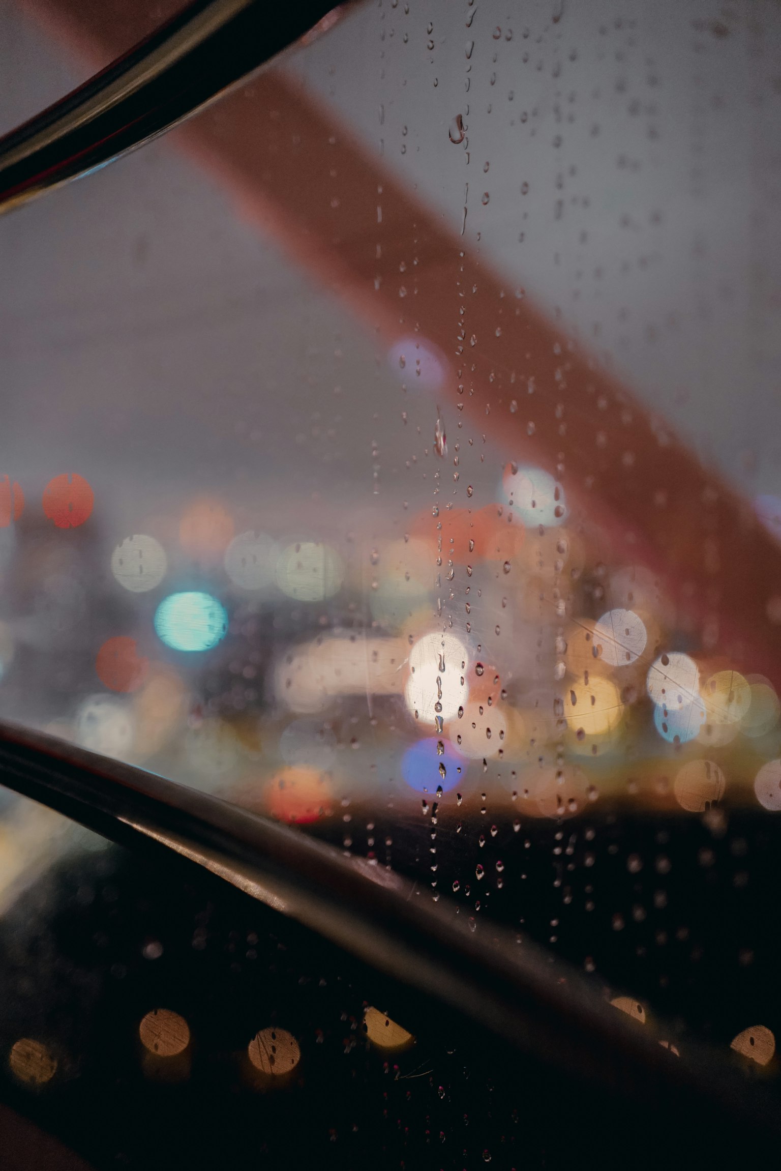 Paesaggio urbano notturno con luci sfocate attraverso una finestra bagnata