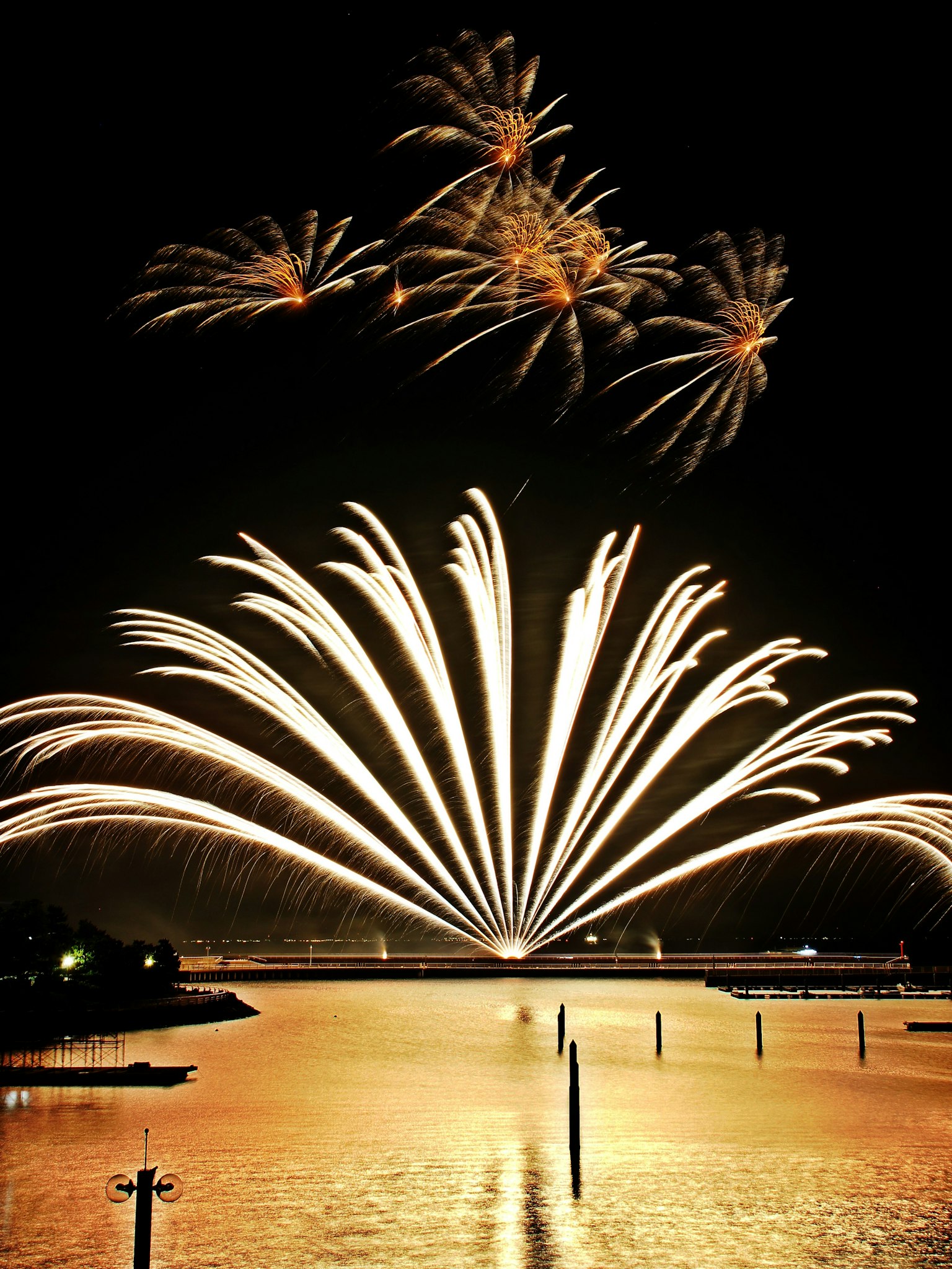 Spectacular fireworks display in the night sky with reflections on the water