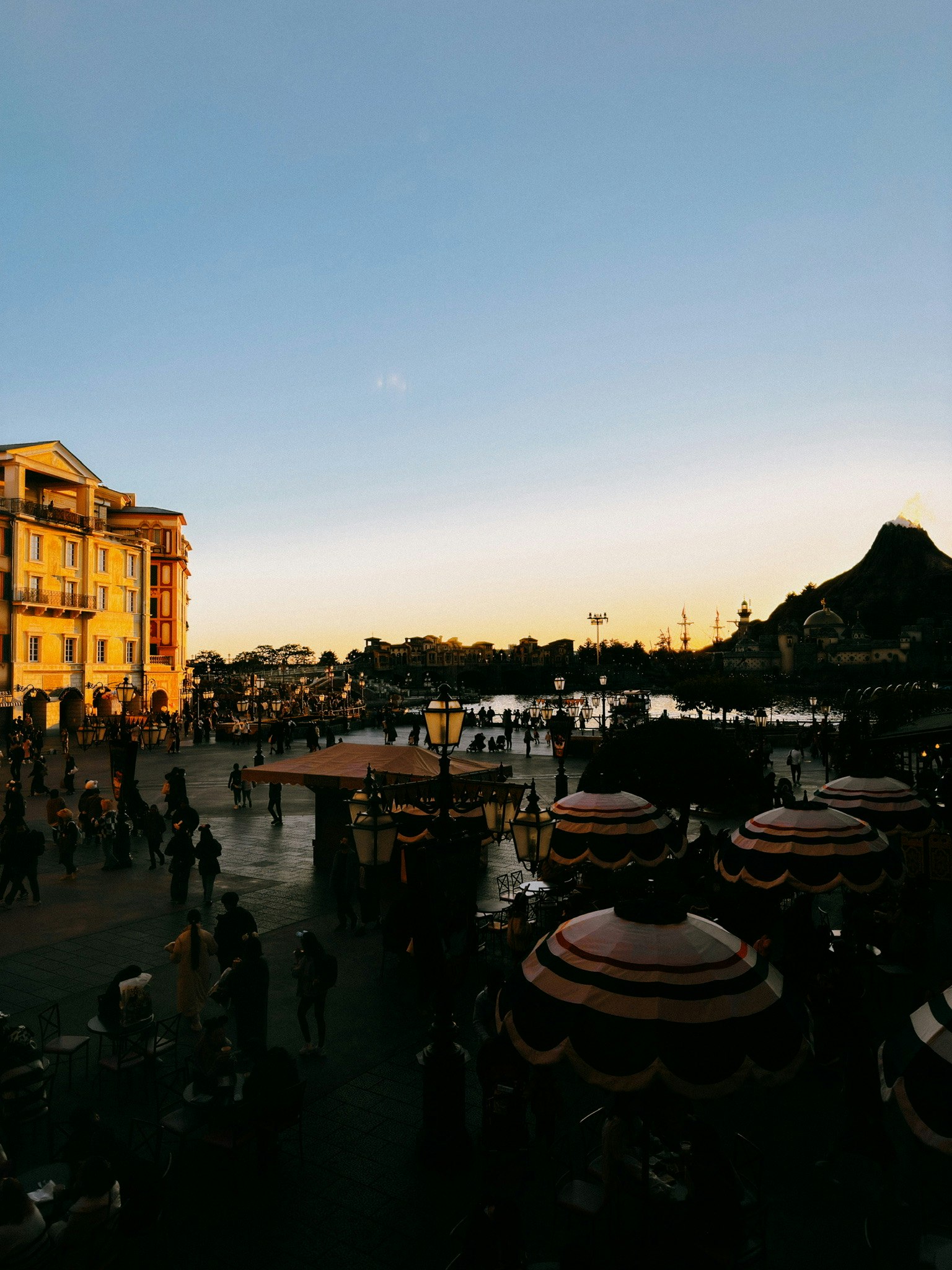 Vue au coucher du soleil d'un parc d'attractions Foules de personnes rassemblées Carrousel et bâtiments visibles