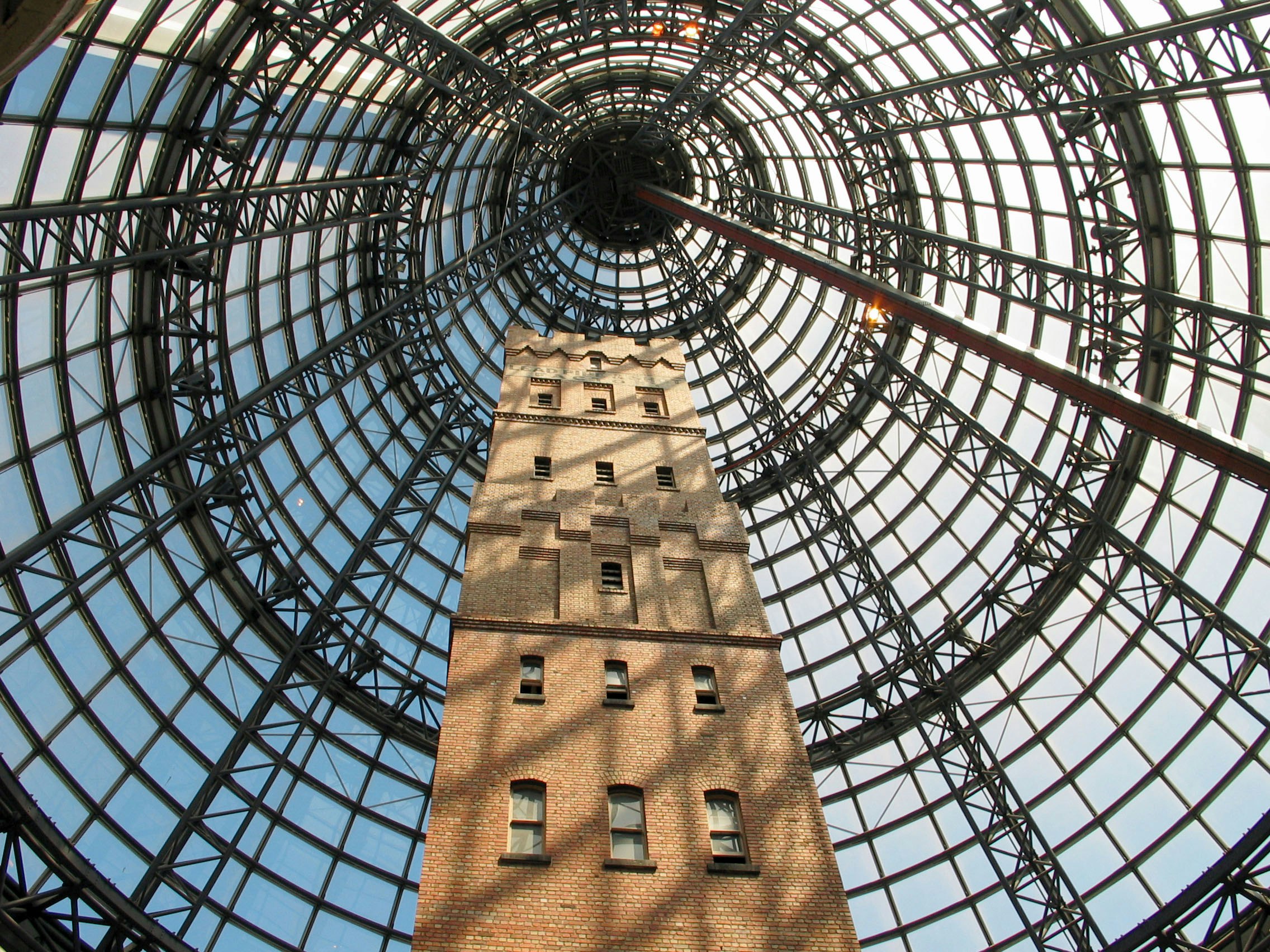 Backsteinturm ragt unter einer kuppelförmigen Glasdecke empor