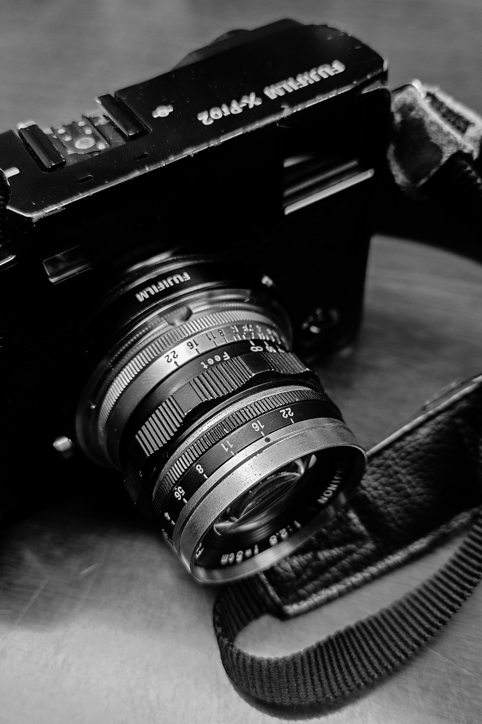 Gros plan d'un appareil photo classique en noir et blanc avec objectif et sangle visibles