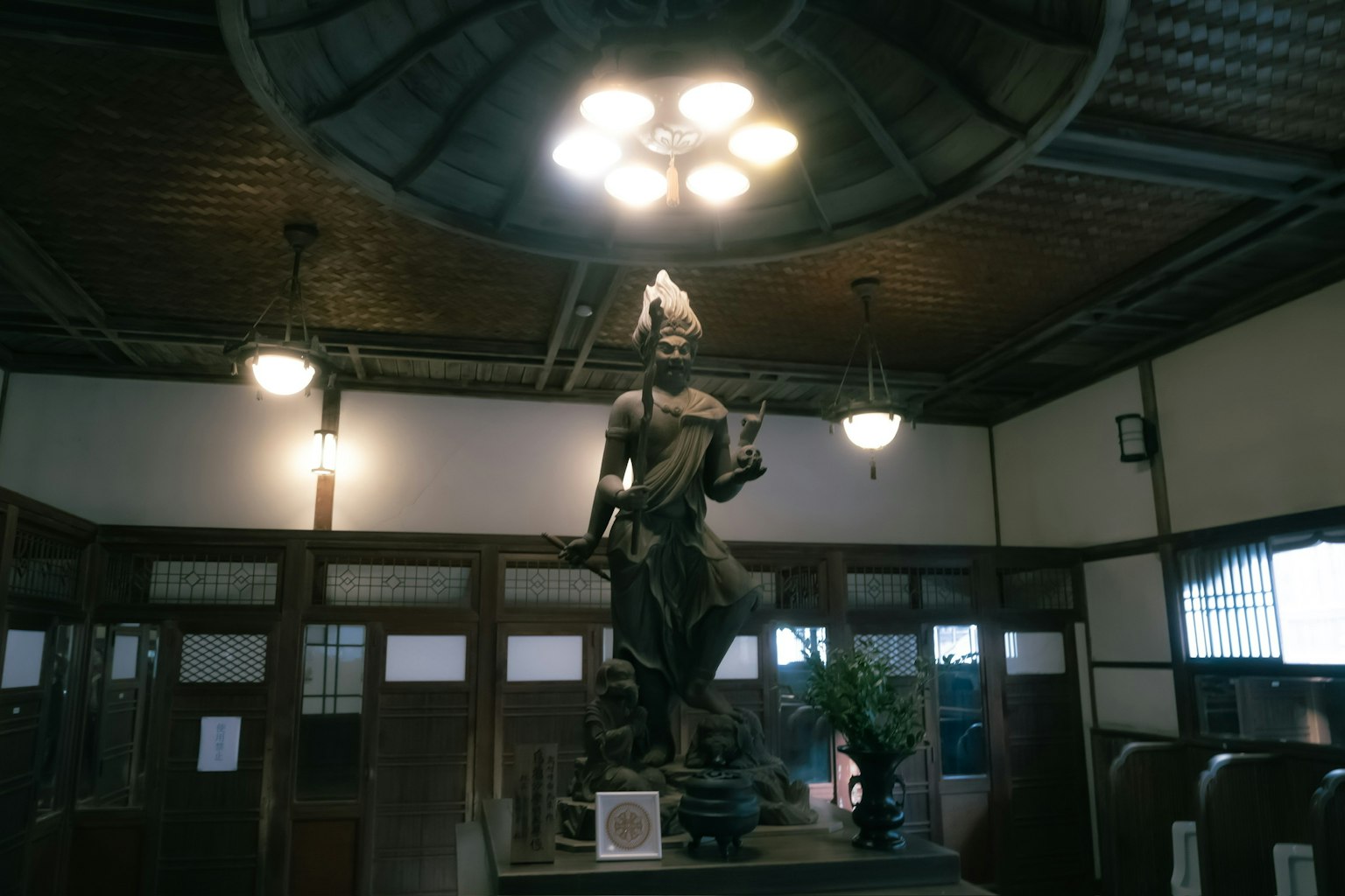 Statua di una divinità all'interno con lampade sopra