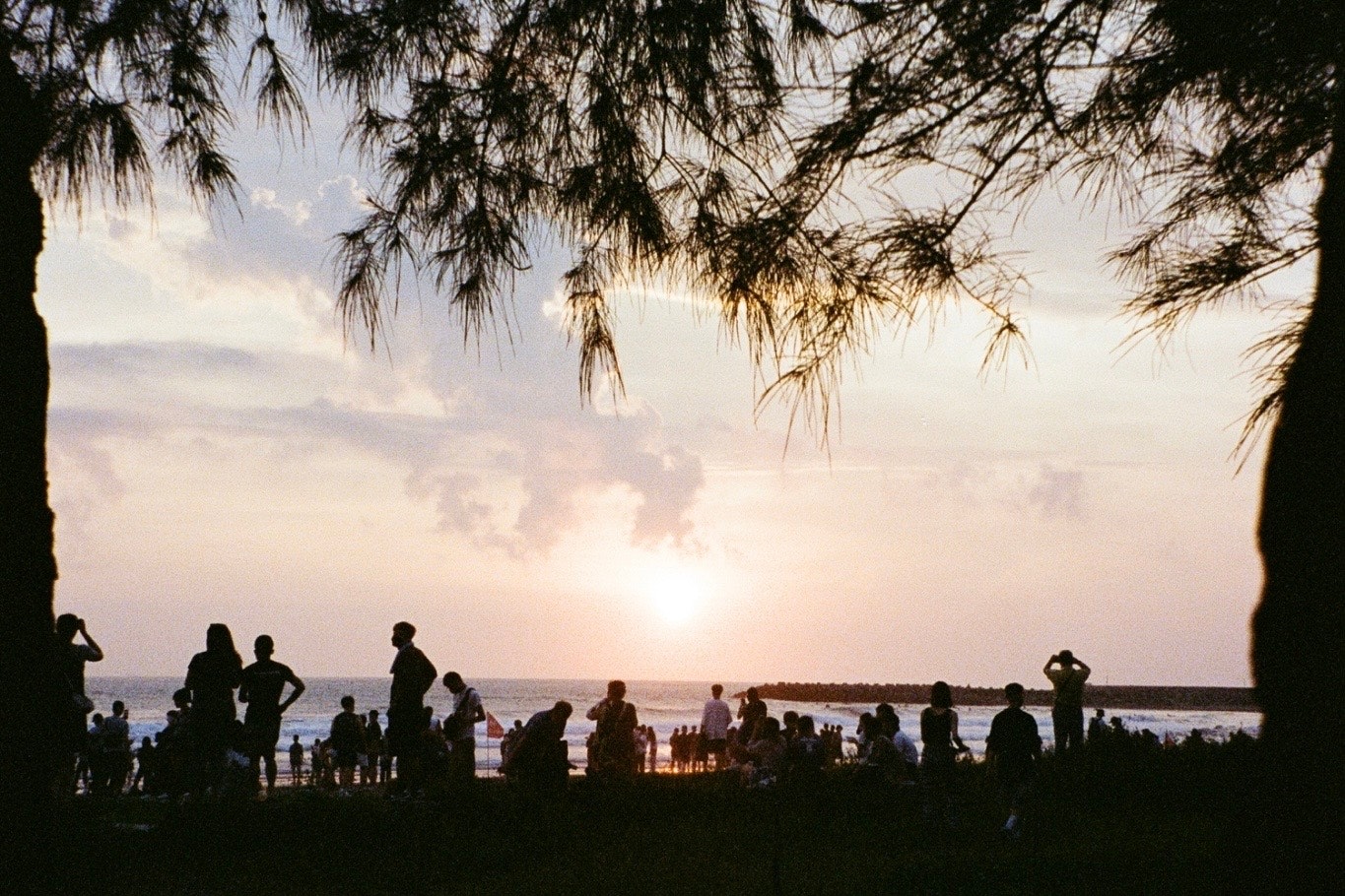 scène de plage au coucher du soleil avec des personnes rassemblées
