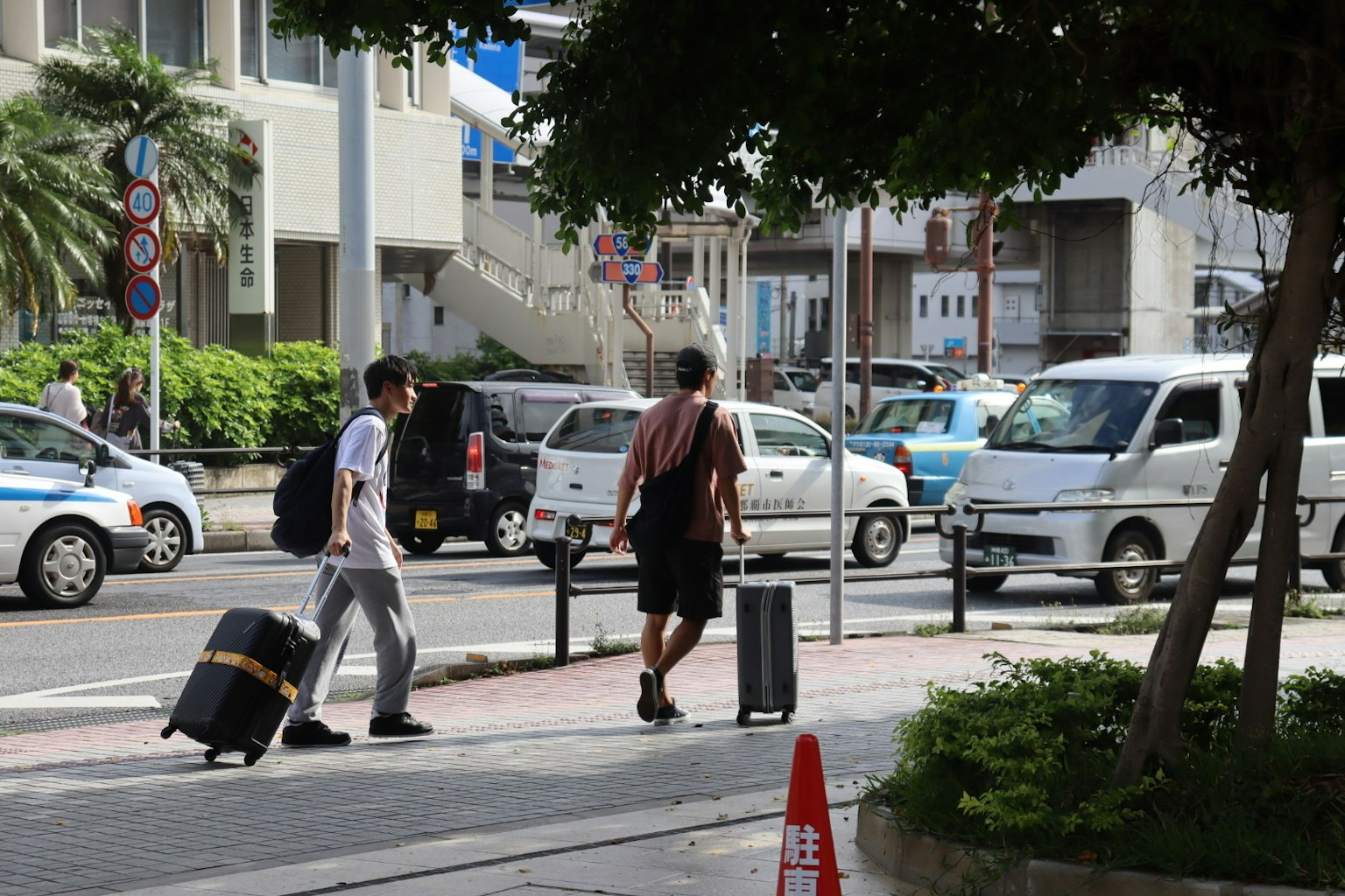 Due viaggiatori che attraversano la strada con valigie