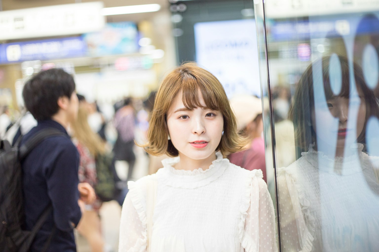 Portrait of a young woman smiling at a station surrounded by people