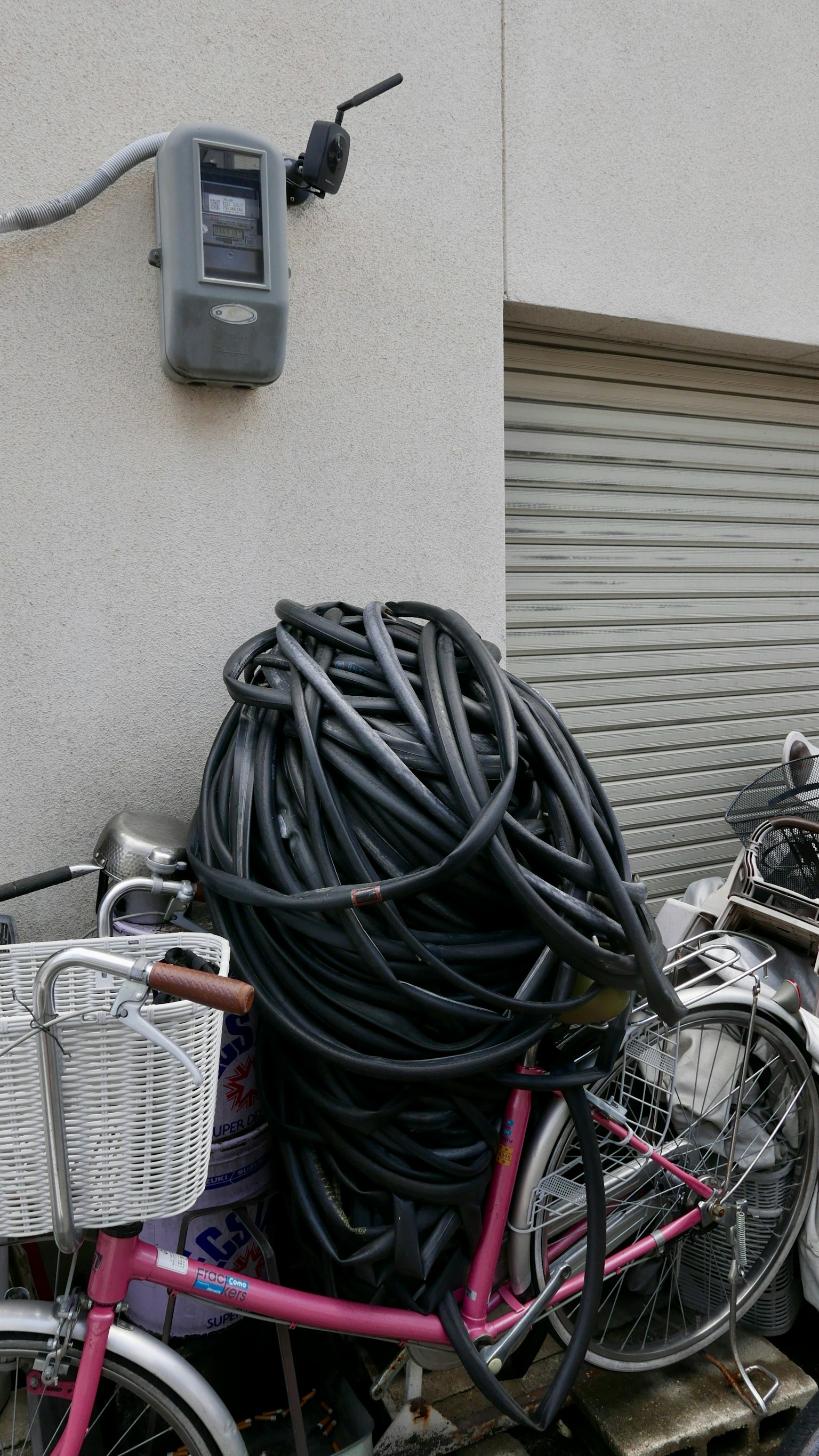 Un mucchio di tubi neri dietro una bicicletta accanto a un contatore montato a muro