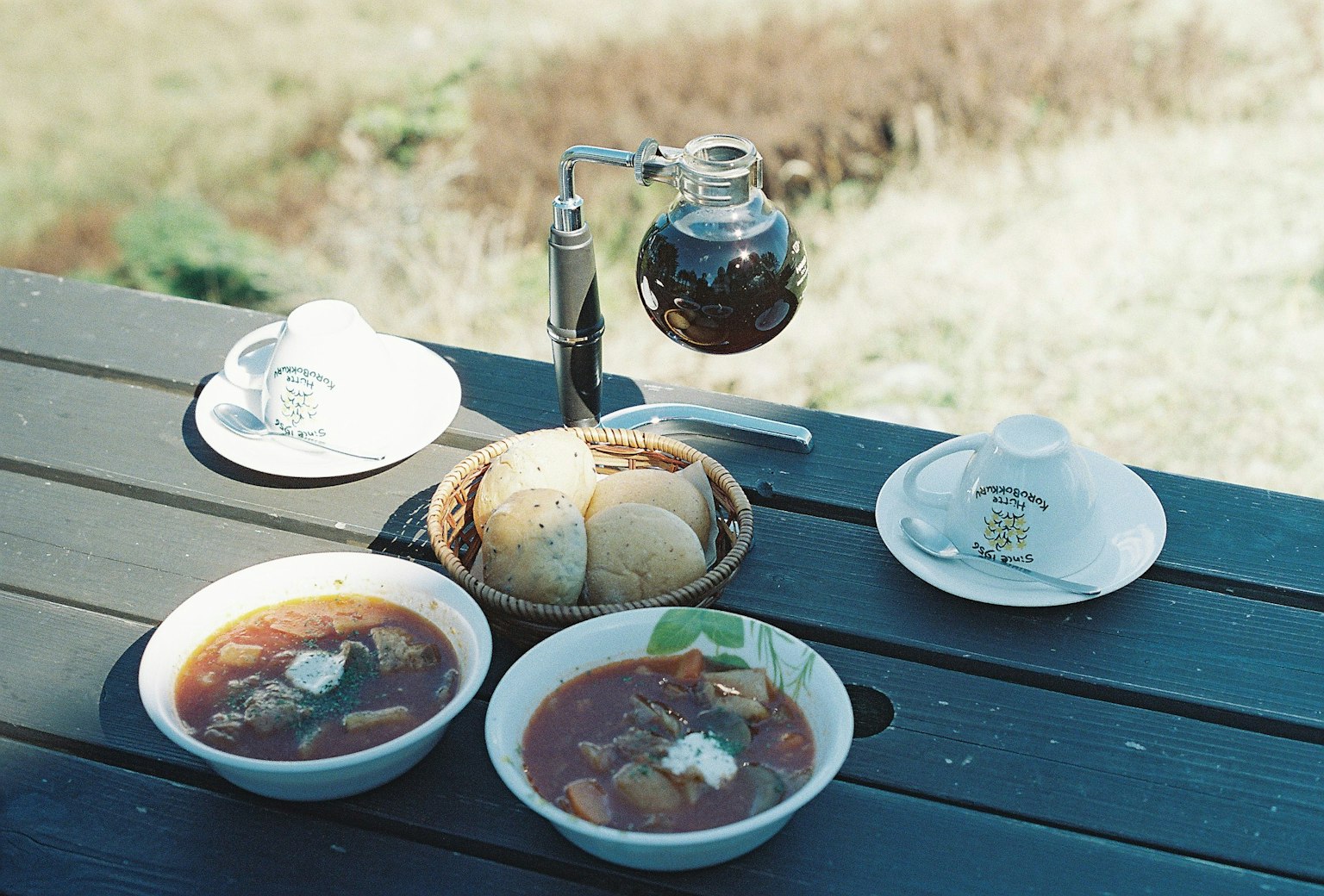 Escena de comida al aire libre con dos tazones de sopa caliente y pan