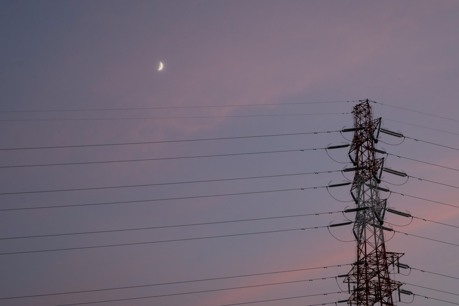 Luna nel cielo al crepuscolo con linee elettriche