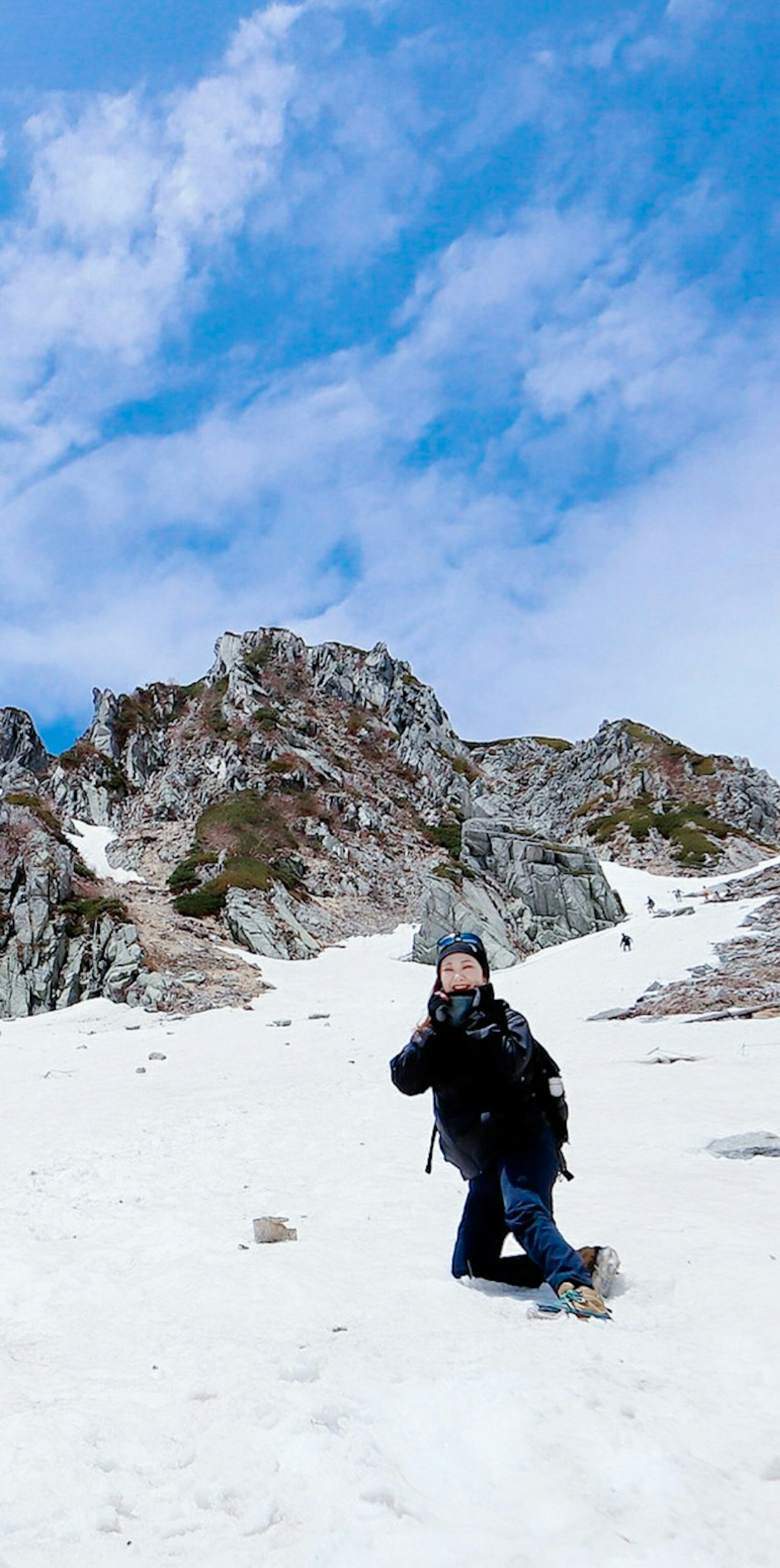 Wanderer posiert im Schnee vor einer zerklüfteten Berglandschaft