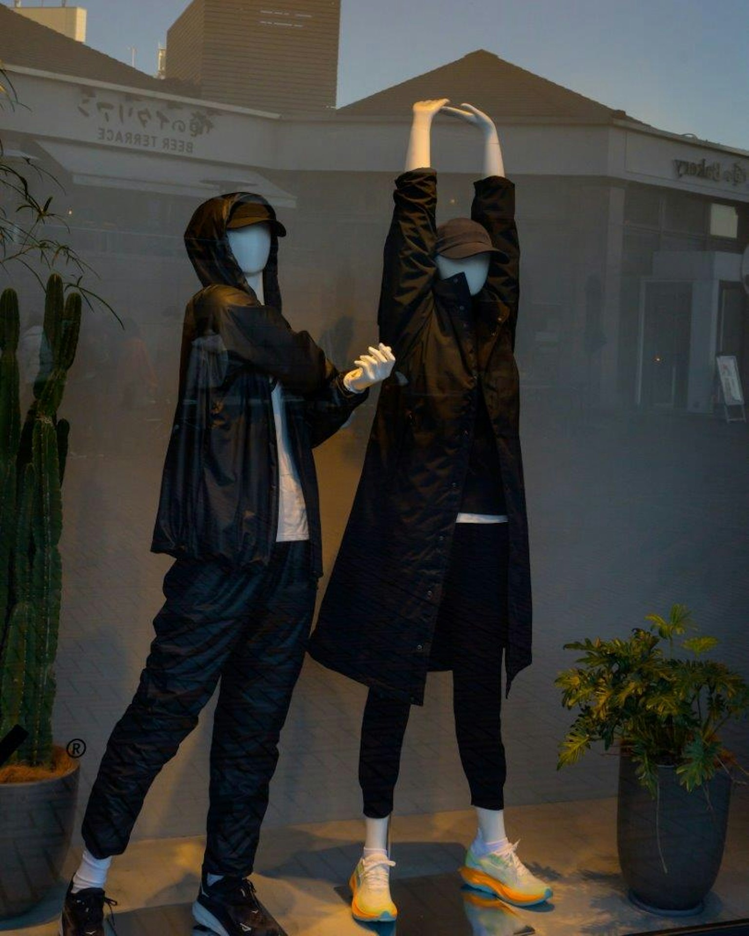 Dua manekin berpakaian hitam berpose di jendela pameran yang stylish