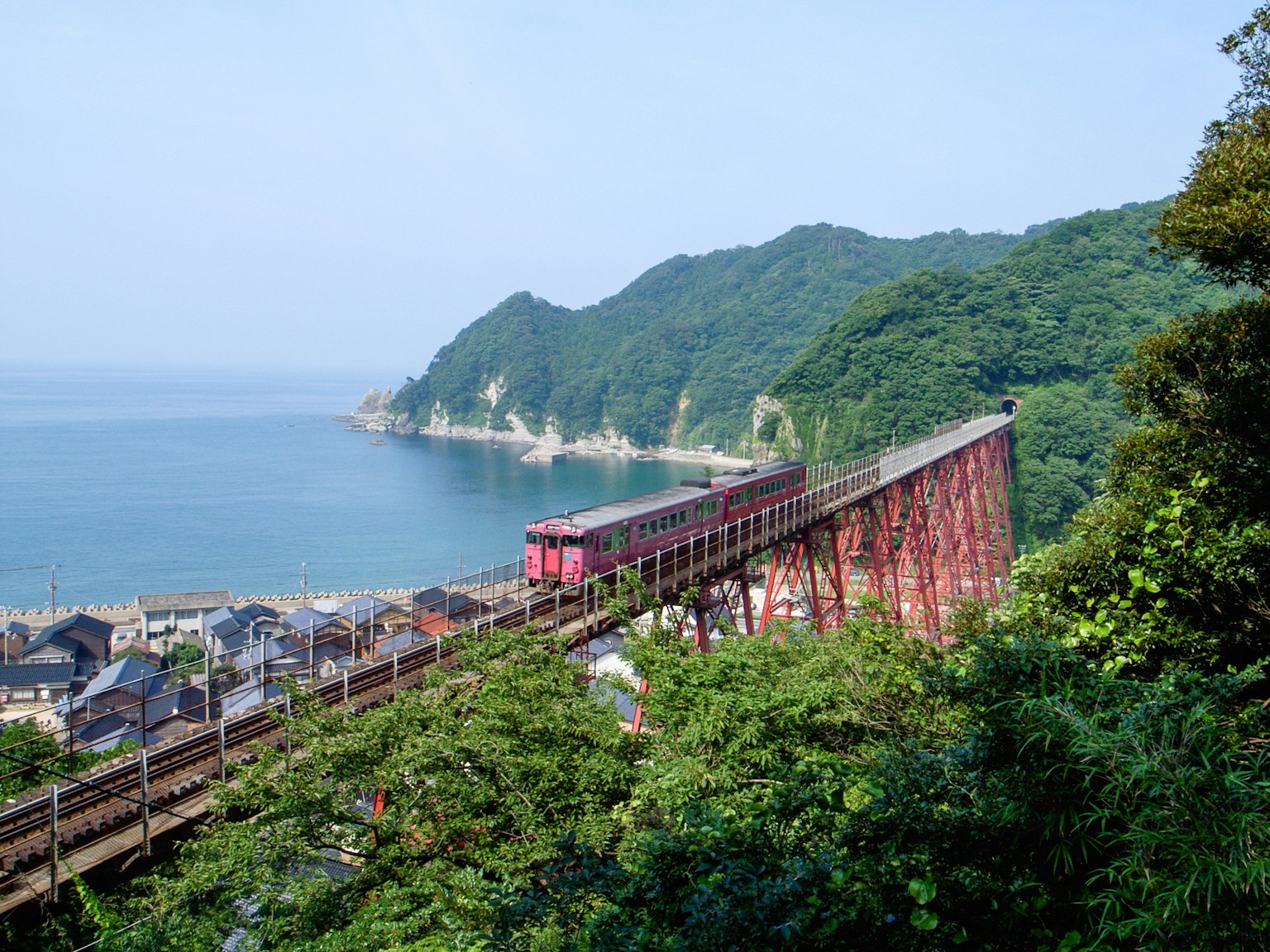 Vue pittoresque d'un pont ferroviaire sur une mer bleue avec des montagnes vertes