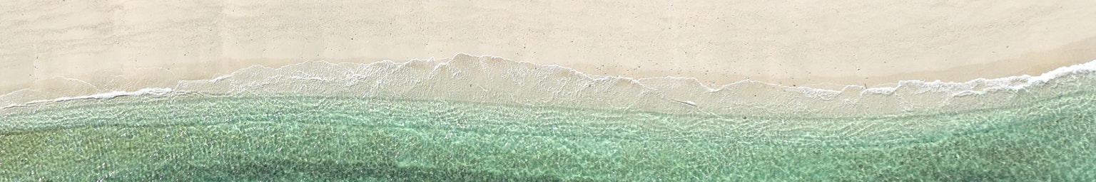 ทิวทัศน์ที่เงียบสงบของมหาสมุทรสีน้ำเงินที่พบกับชายหาดทราย