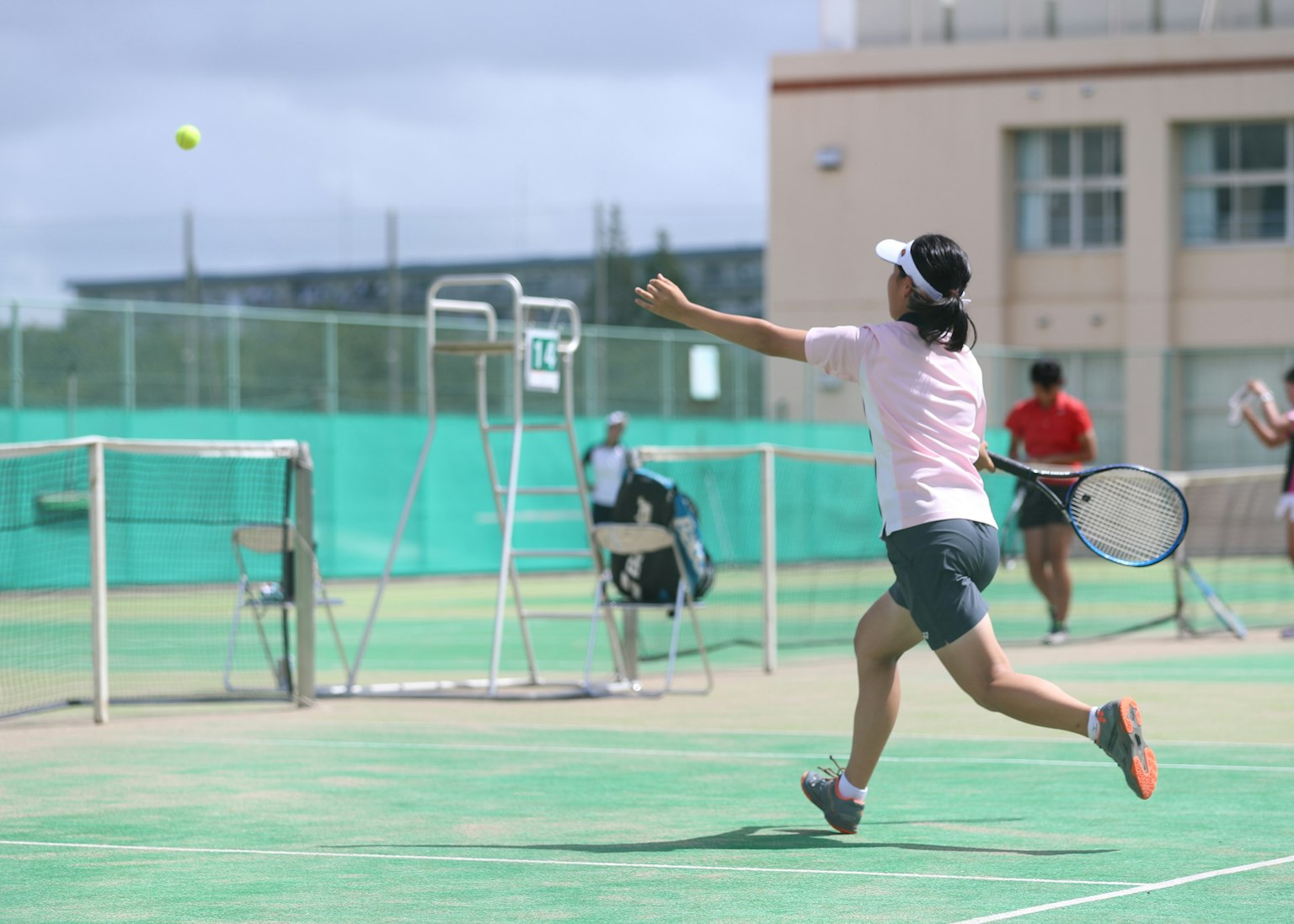 Pemain tenis wanita memukul bola di lapangan