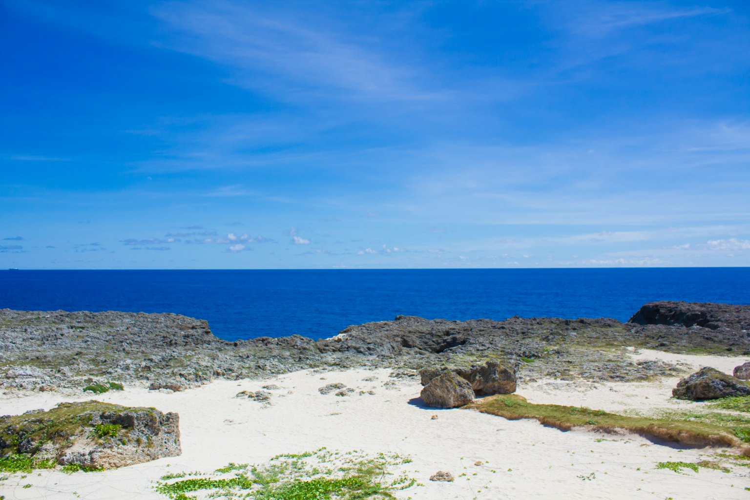 Vista de playa escénica con océano azul y cielo que muestra rocas y arena