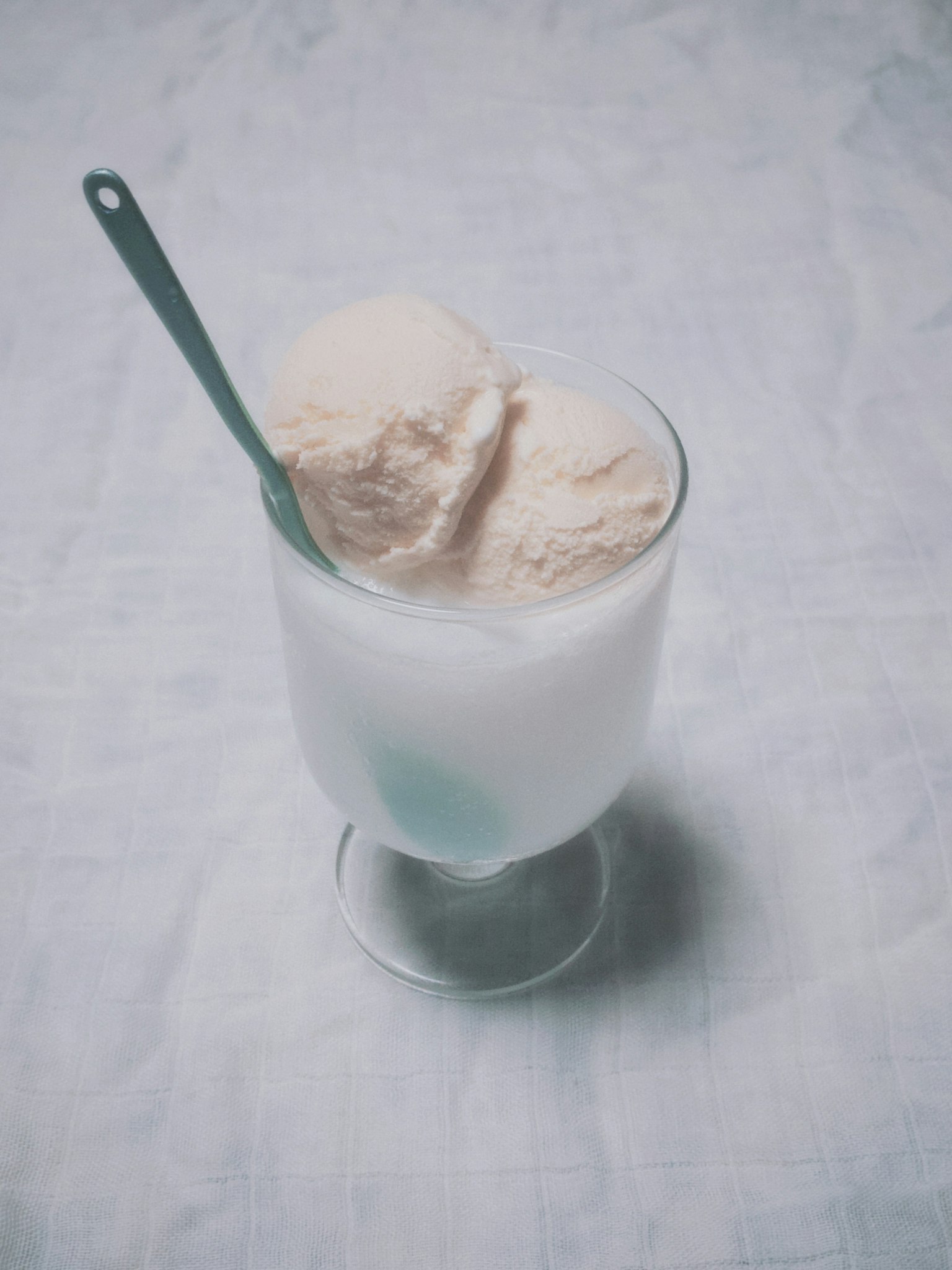 Un vaso con dos bolas de helado y una cuchara azul