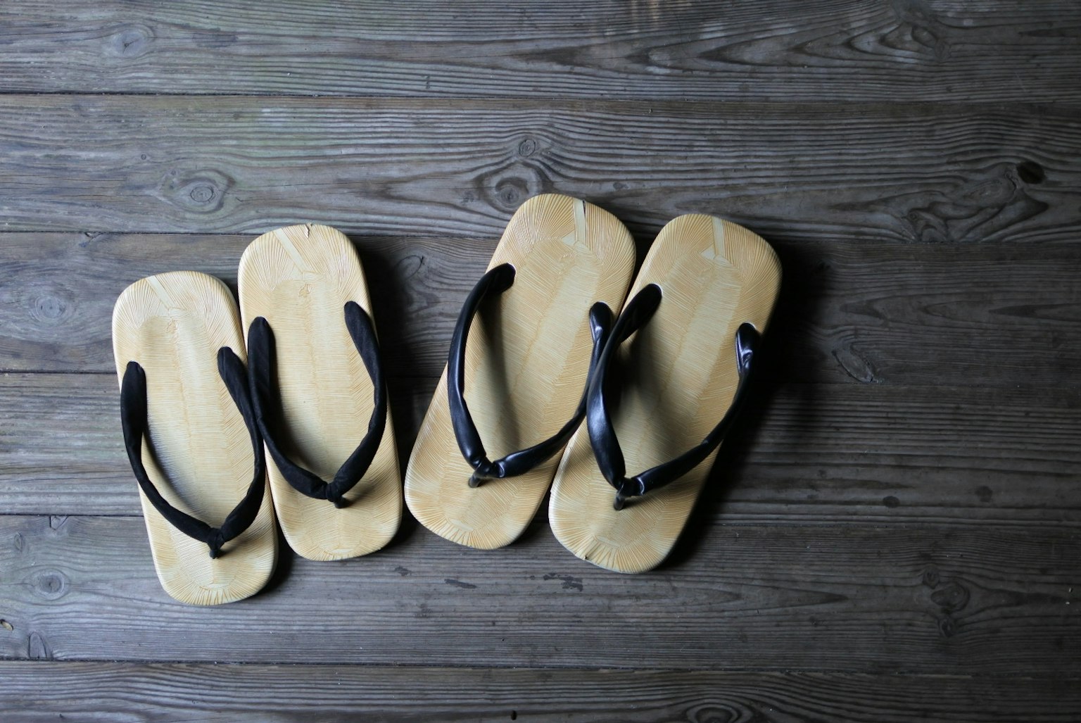Dos pares de sandalias de madera dispuestas sobre una superficie de madera