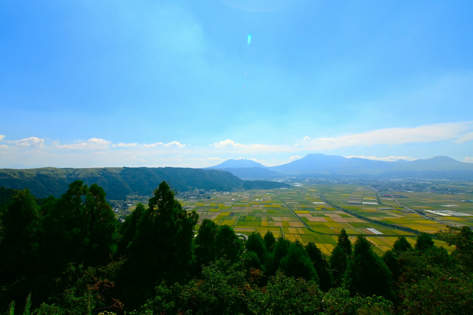 Weite grüne Landschaft unter einem klaren blauen Himmel mit fernen Bergen