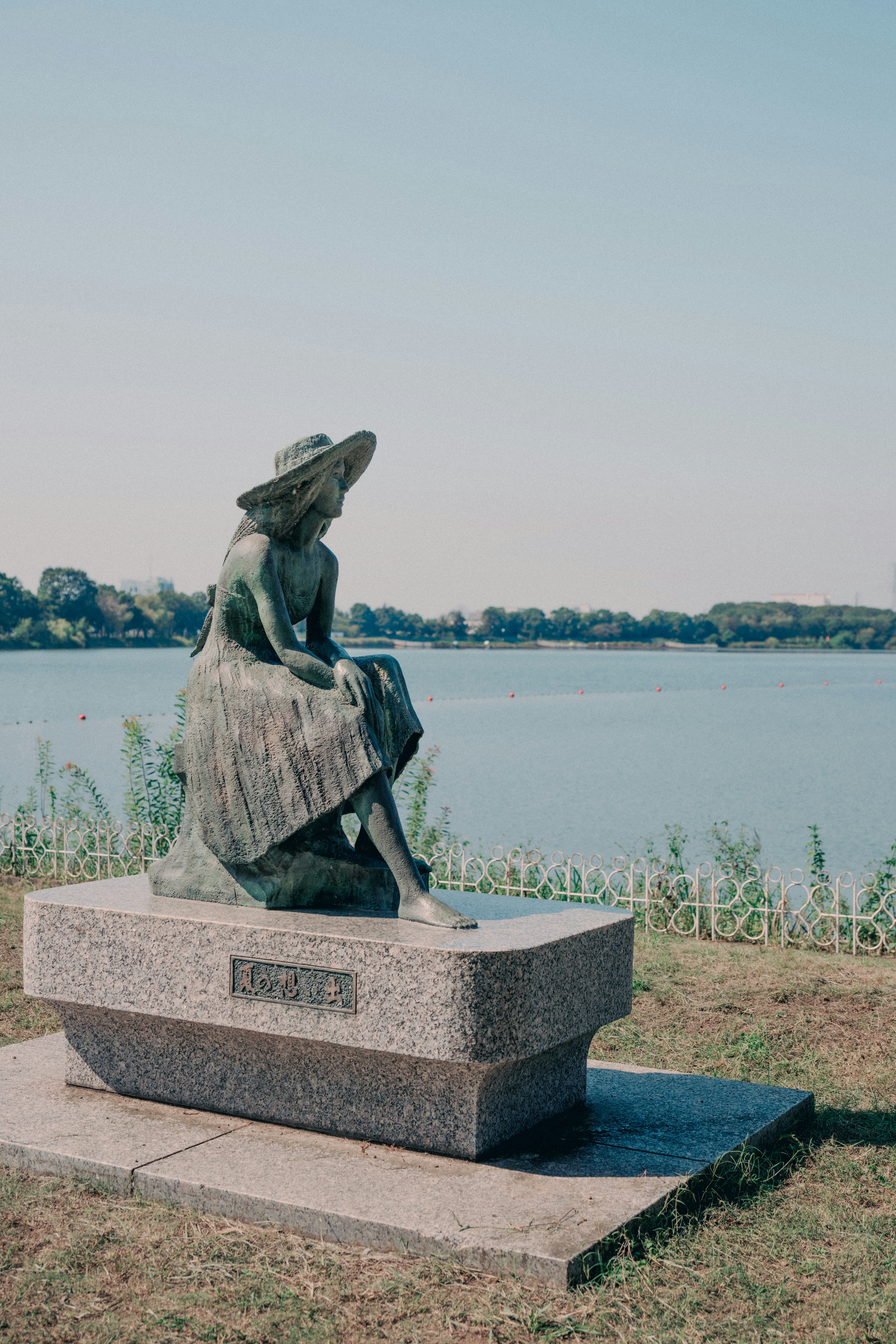 Frauenskulptur auf einem Sockel am Seeufer