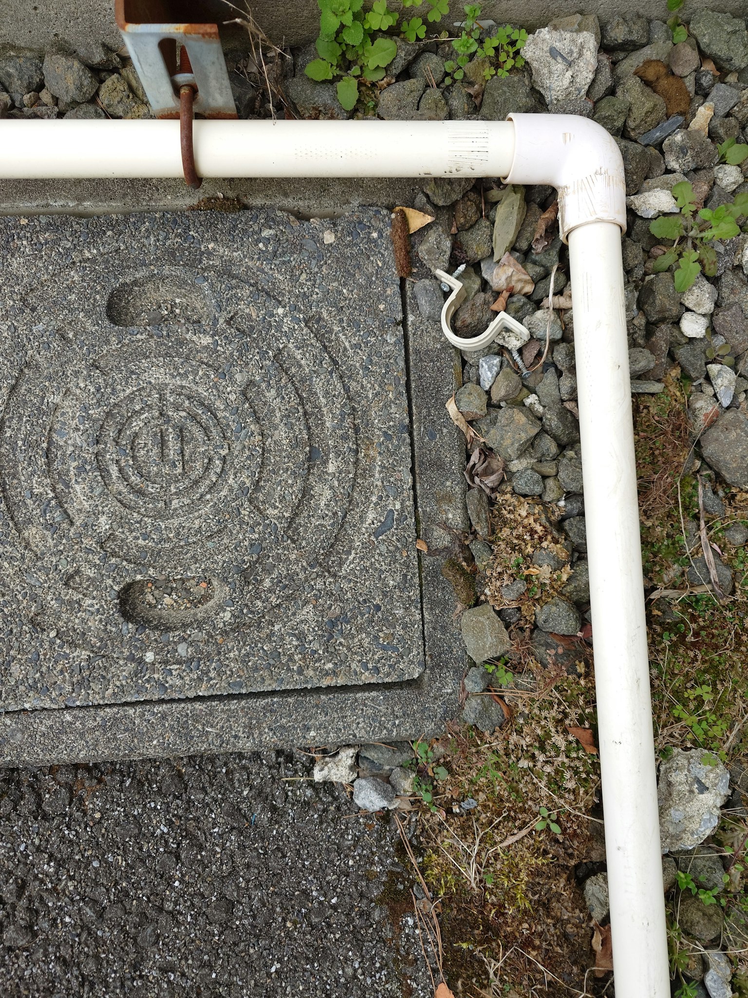 Foto di un terreno con un tubo bianco e un coperchio in pietra