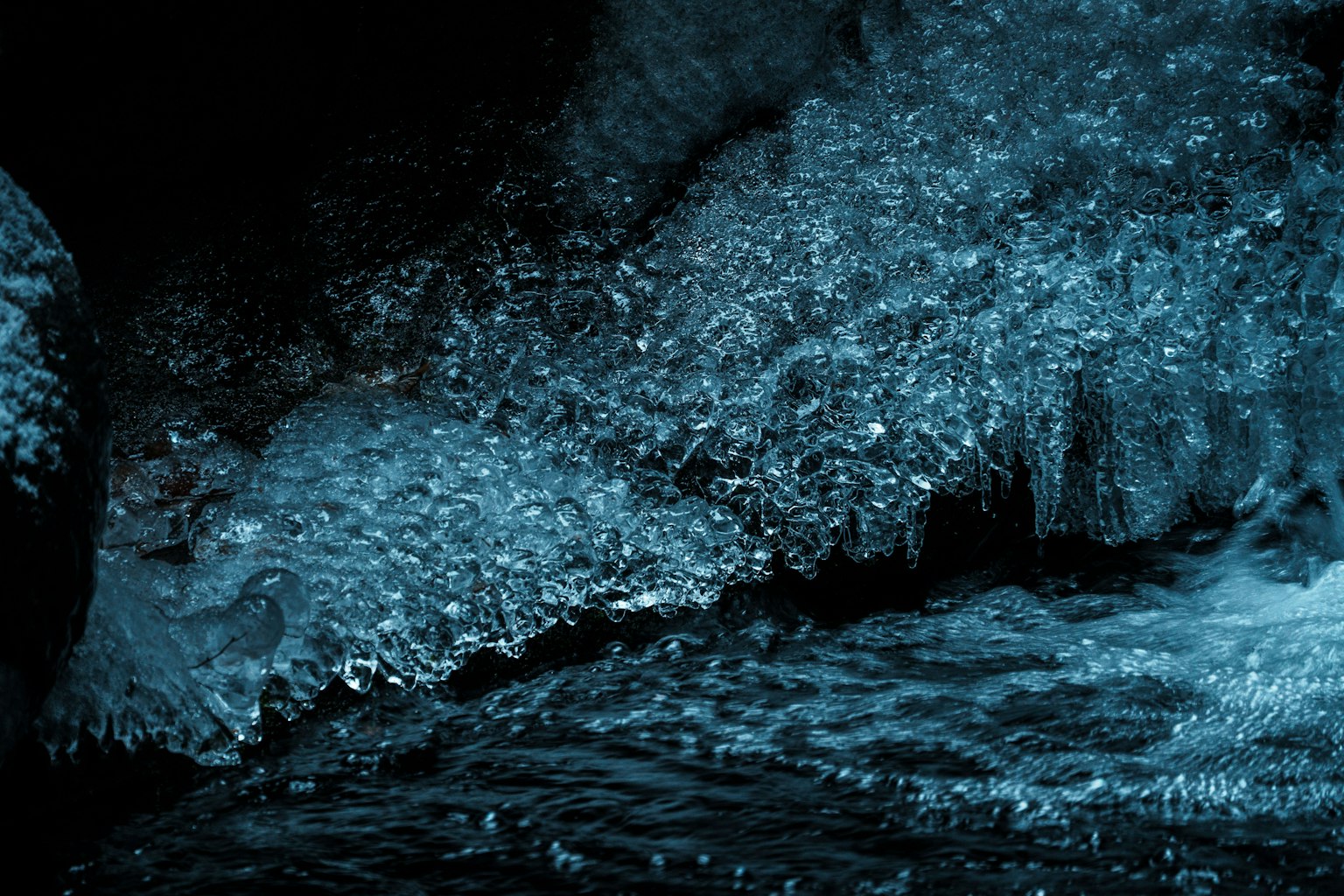 Spritzendes blaues Wasser vor dunklem Hintergrund