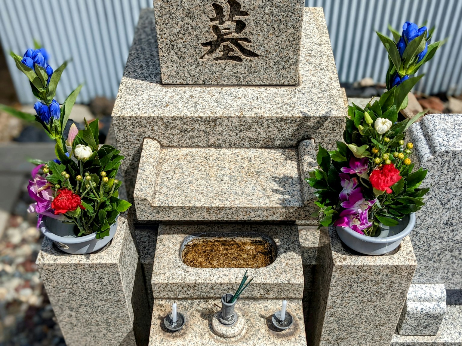 Grabstein mit Blumenarrangements auf beiden Seiten