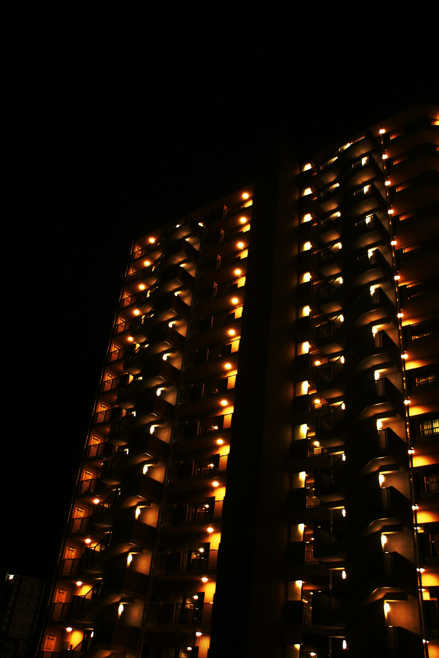 Eksterior gedung tinggi di malam hari dengan balkon yang diterangi