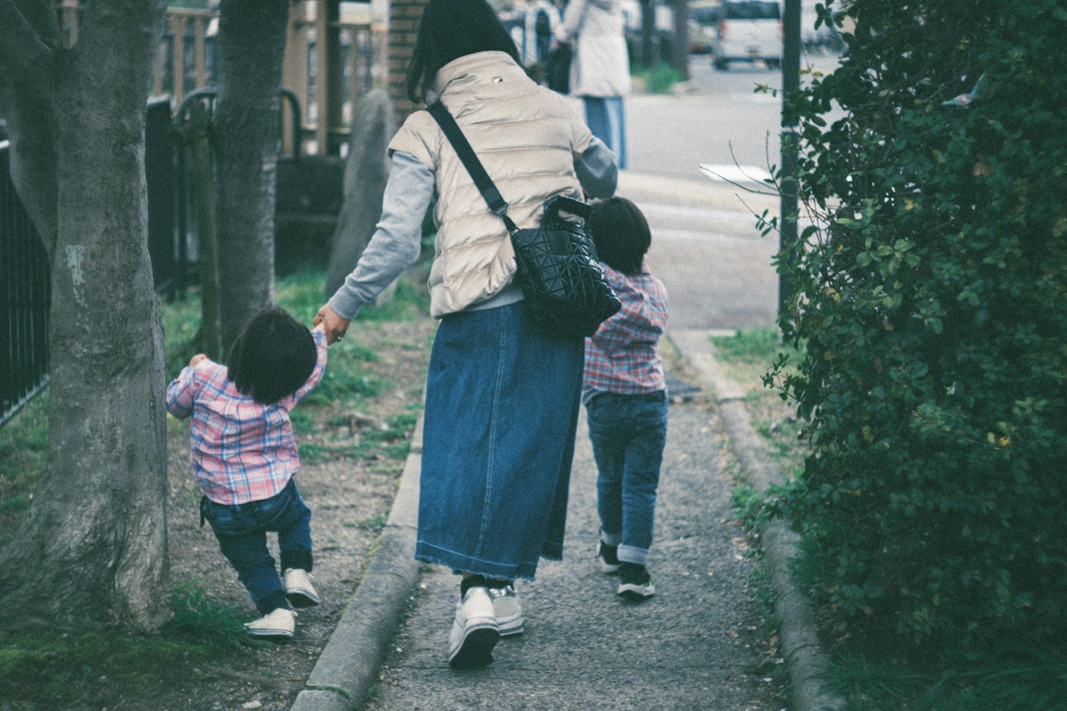一位母親帶著兩個孩子在小路上散步