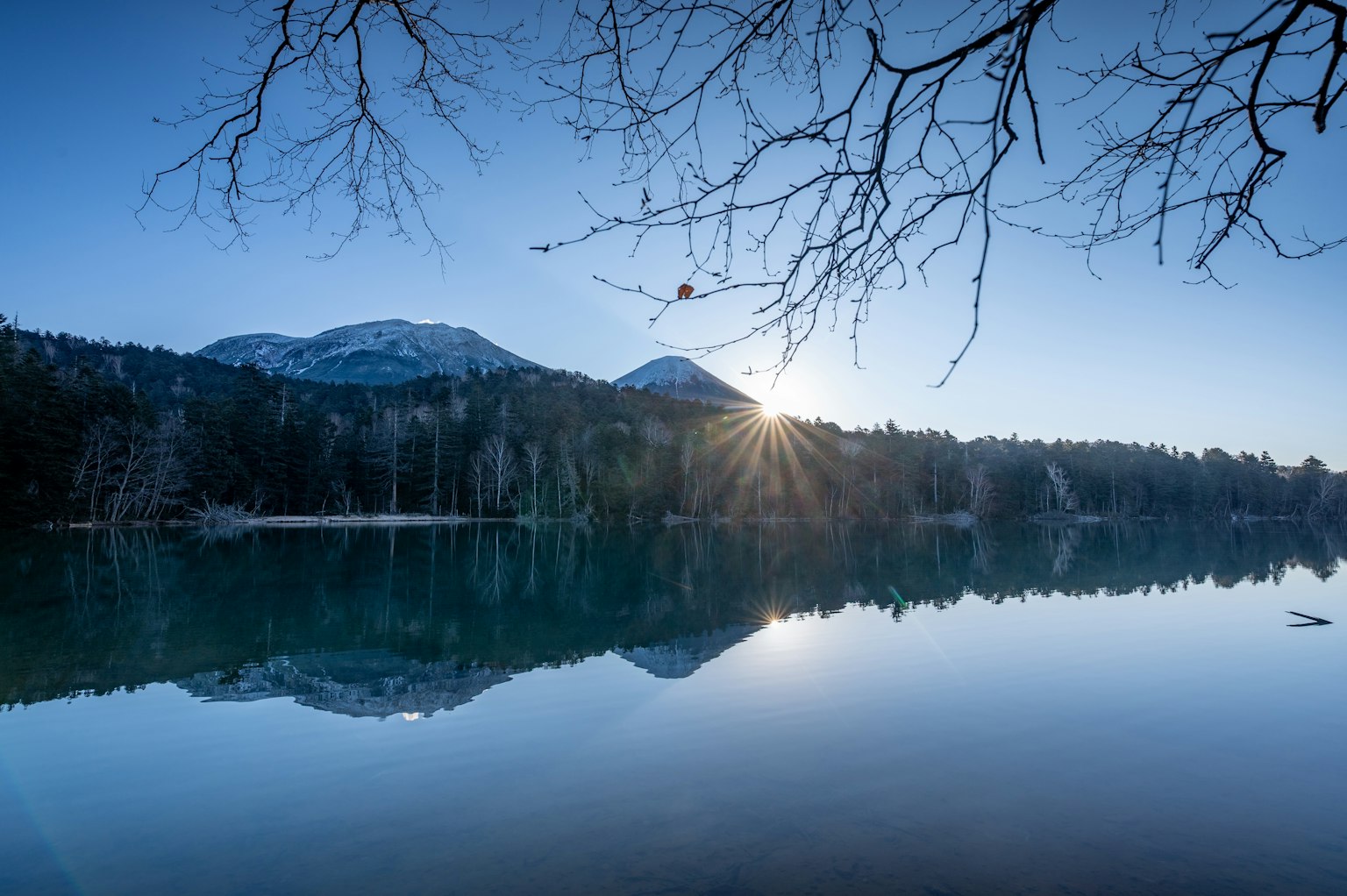 静かな湖と山々の風景 朝日が水面に反射している