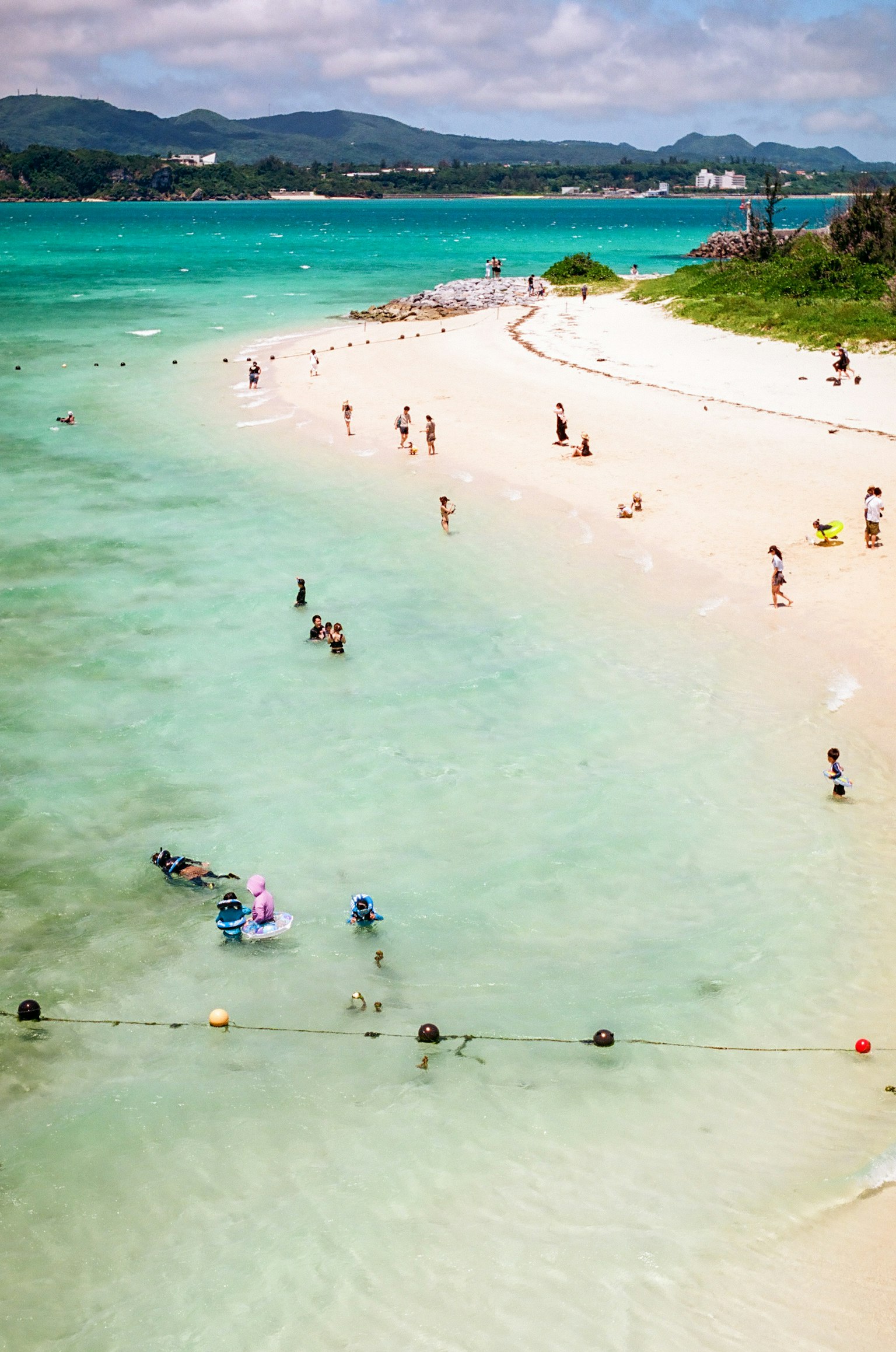 ผู้คนกำลังเพลิดเพลินกับชายหาดที่สวยงามและน้ำที่สงบ