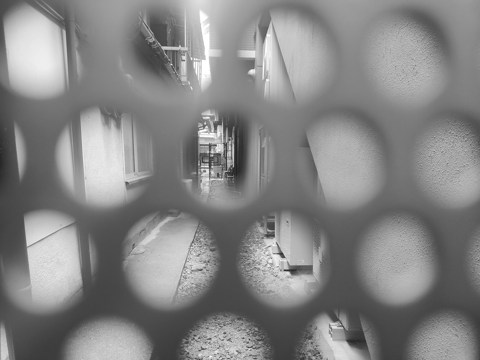 Vista monocromática de un callejón a través de agujeros circulares