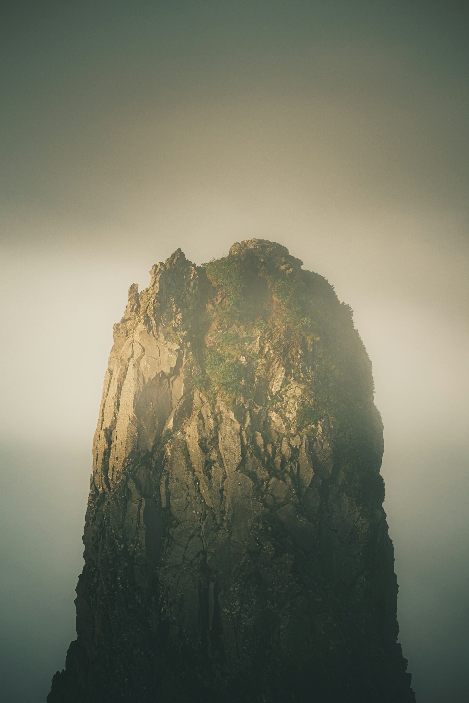 Bild eines Berggipfels, der von Licht umgeben von Nebel beleuchtet wird