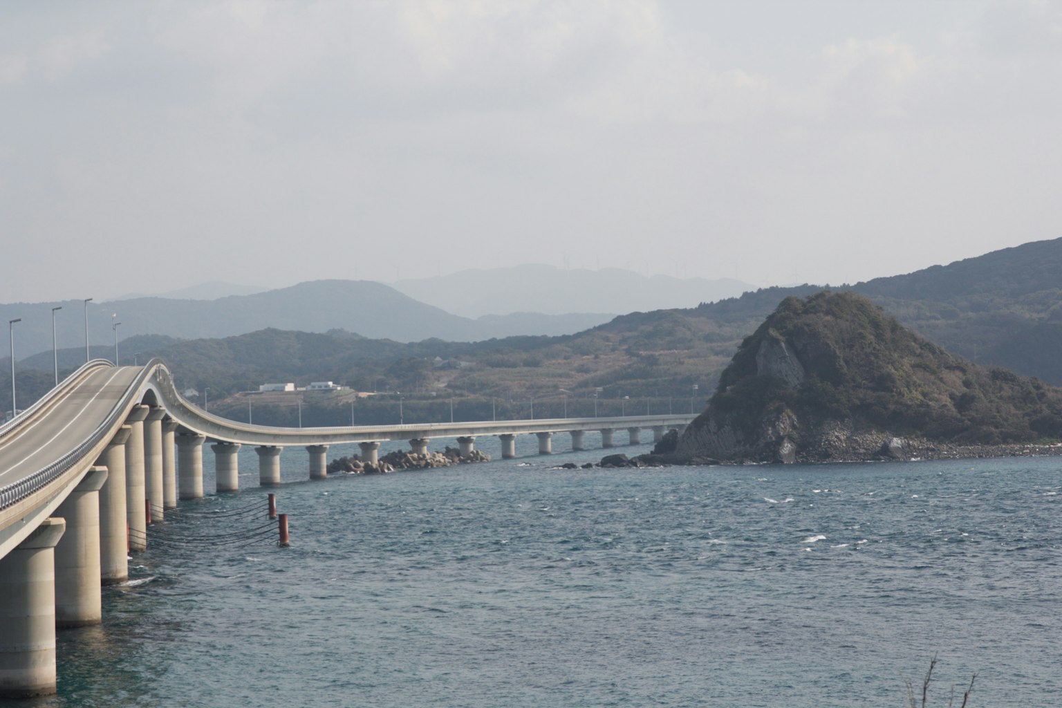 Un puente que cruza el mar con un fondo montañoso