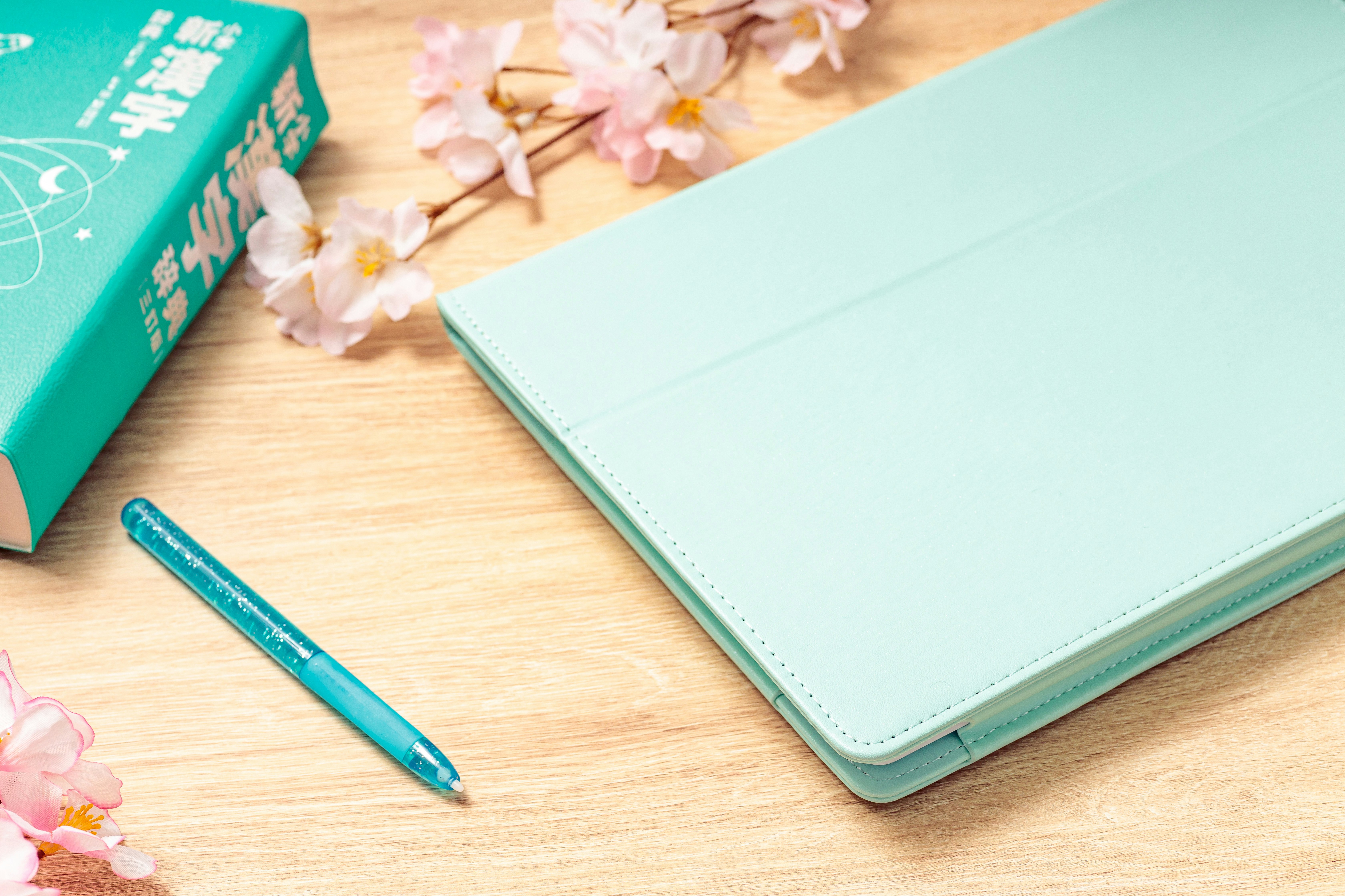 桜の花と新学期のタブレット・辞書が並ぶ机の上